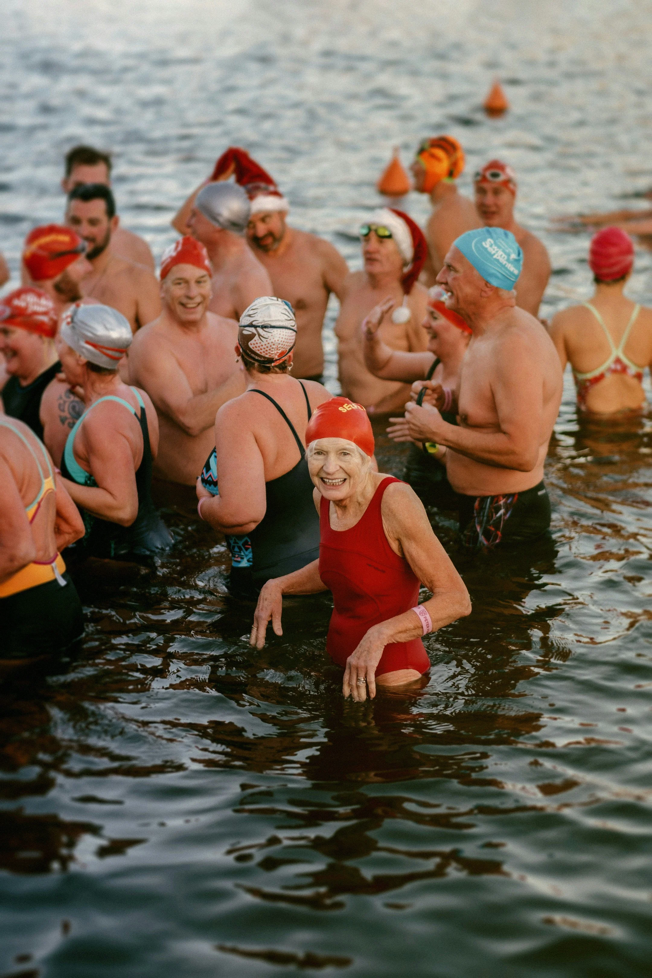 Try something new a group of people in swimwear and caps standing in water, participating in a swimming event.
