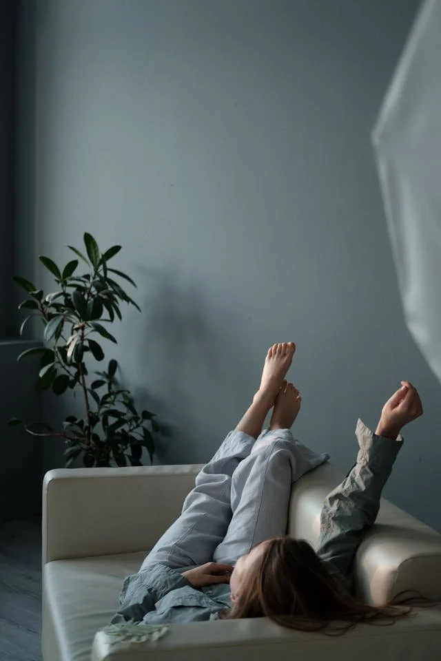 A woman with OCD lounges casually on a sofa indoors, creating a serene and relaxing atmosphere