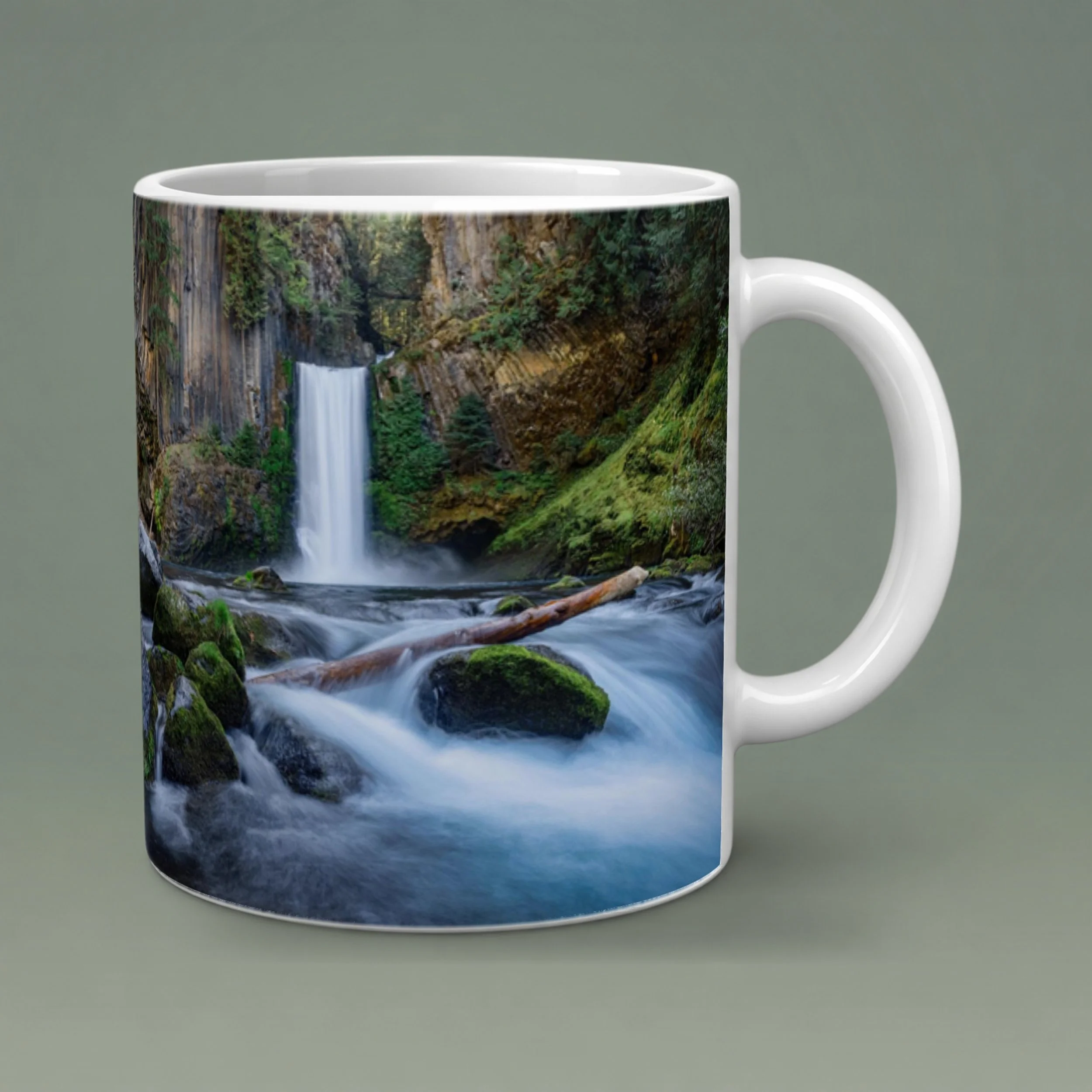 White 11 oz Toketee Falls photo mug with softly shaded ceramic, a rounded handle, and a gray-green background.