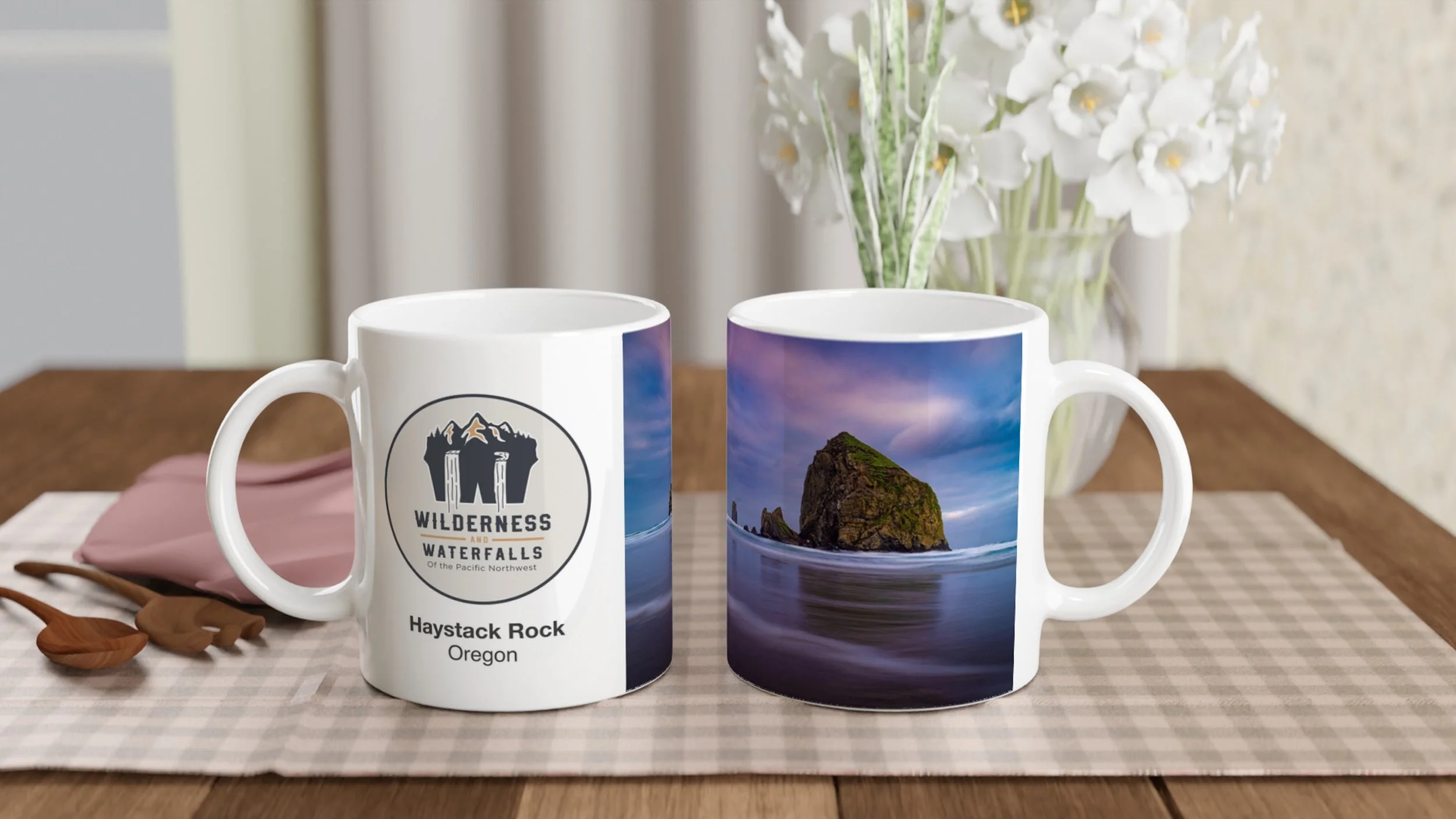Two views of the same Haystack Rock photo mug on a dining table, showing the Wilderness & Waterfalls logo and coastal photograph.