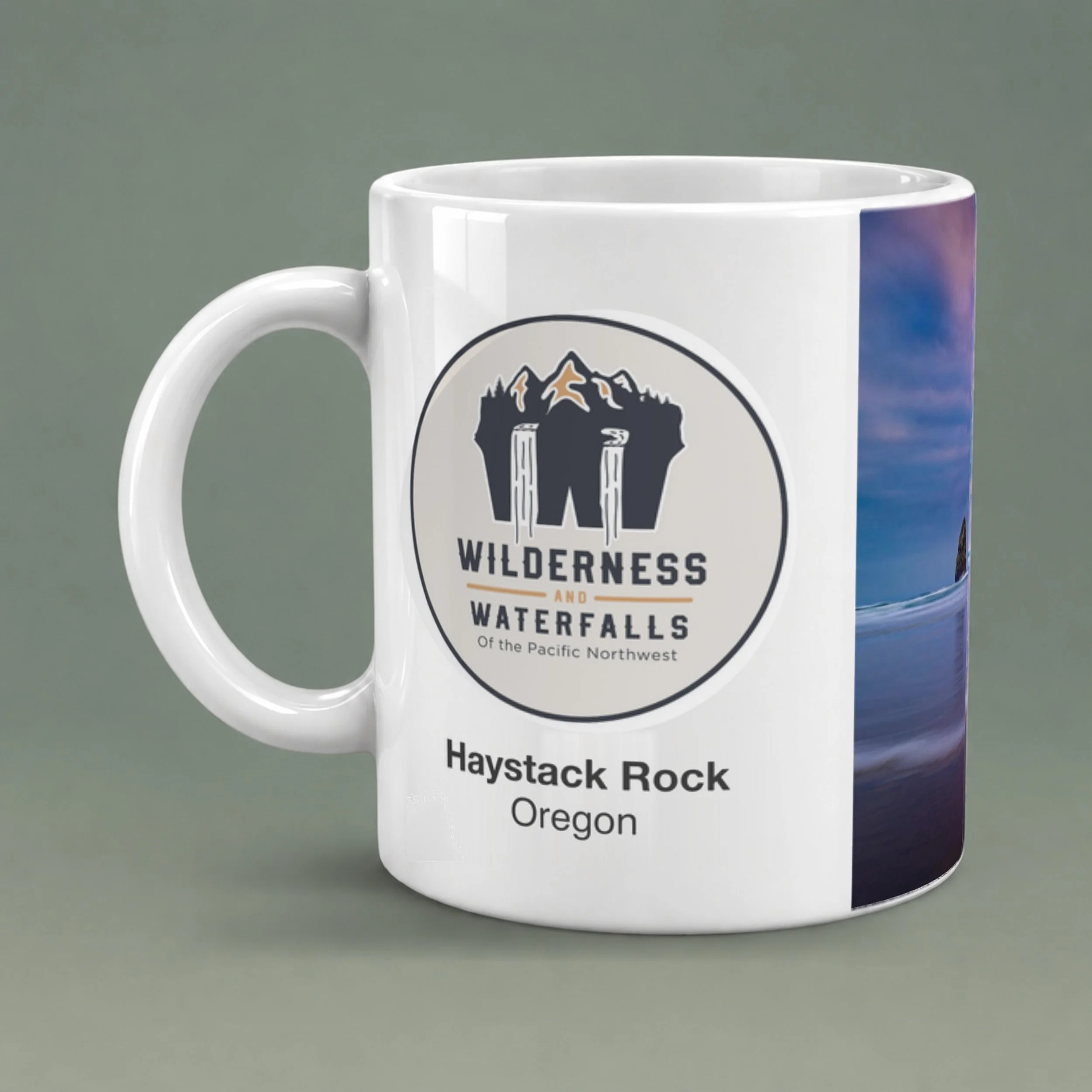 White ceramic mug showing the Wilderness & Waterfalls logo and Haystack Rock, Oregon text, with glossy ceramic and a shaded rounded handle.
