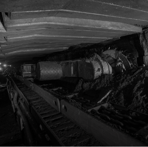 Underground mining operation with heavy machinery drilling into rock walls.