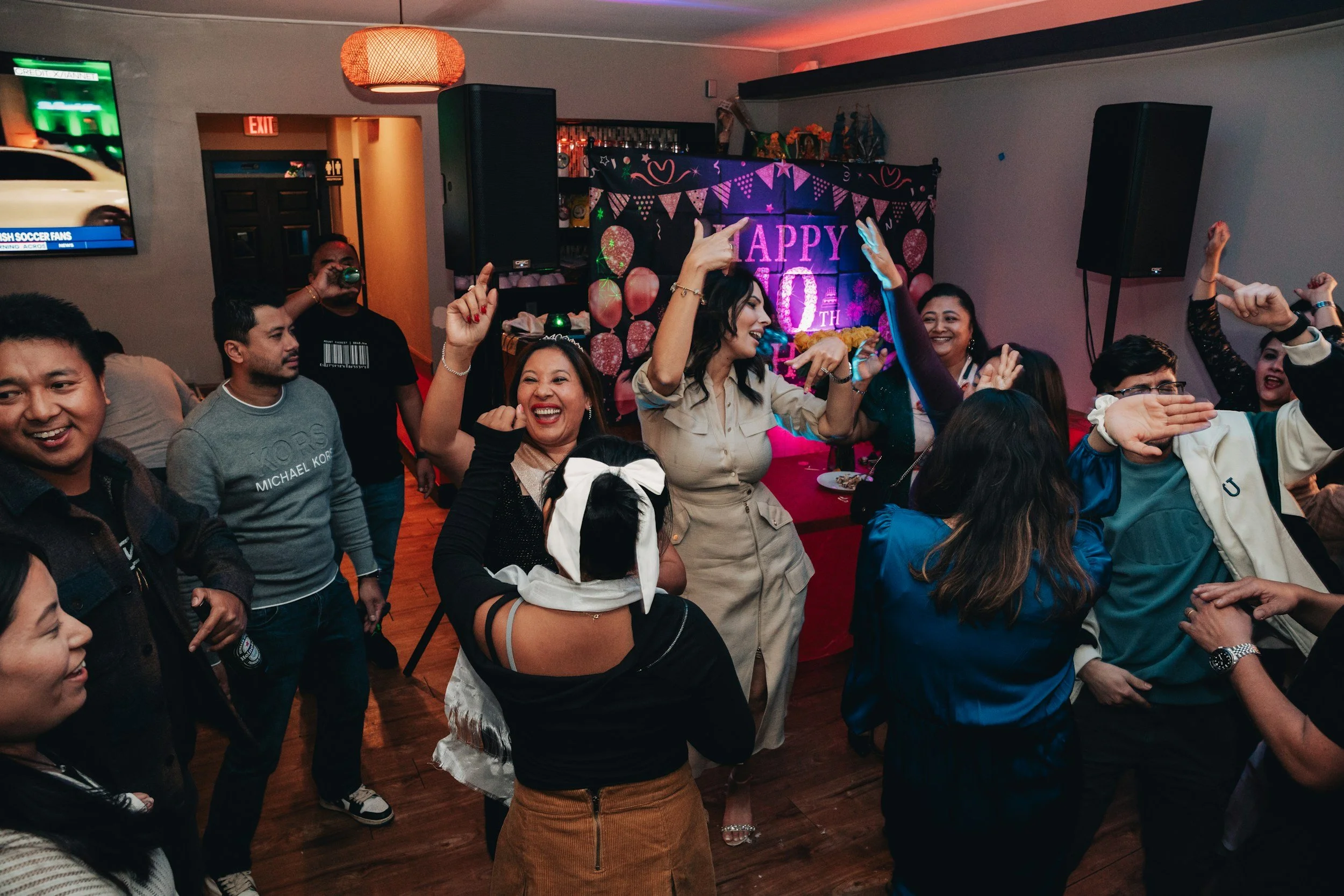 People dancing and celebrating at a 50th birthday party with a colorful backdrop that says "HAPPY 50TH" in a decorated room.