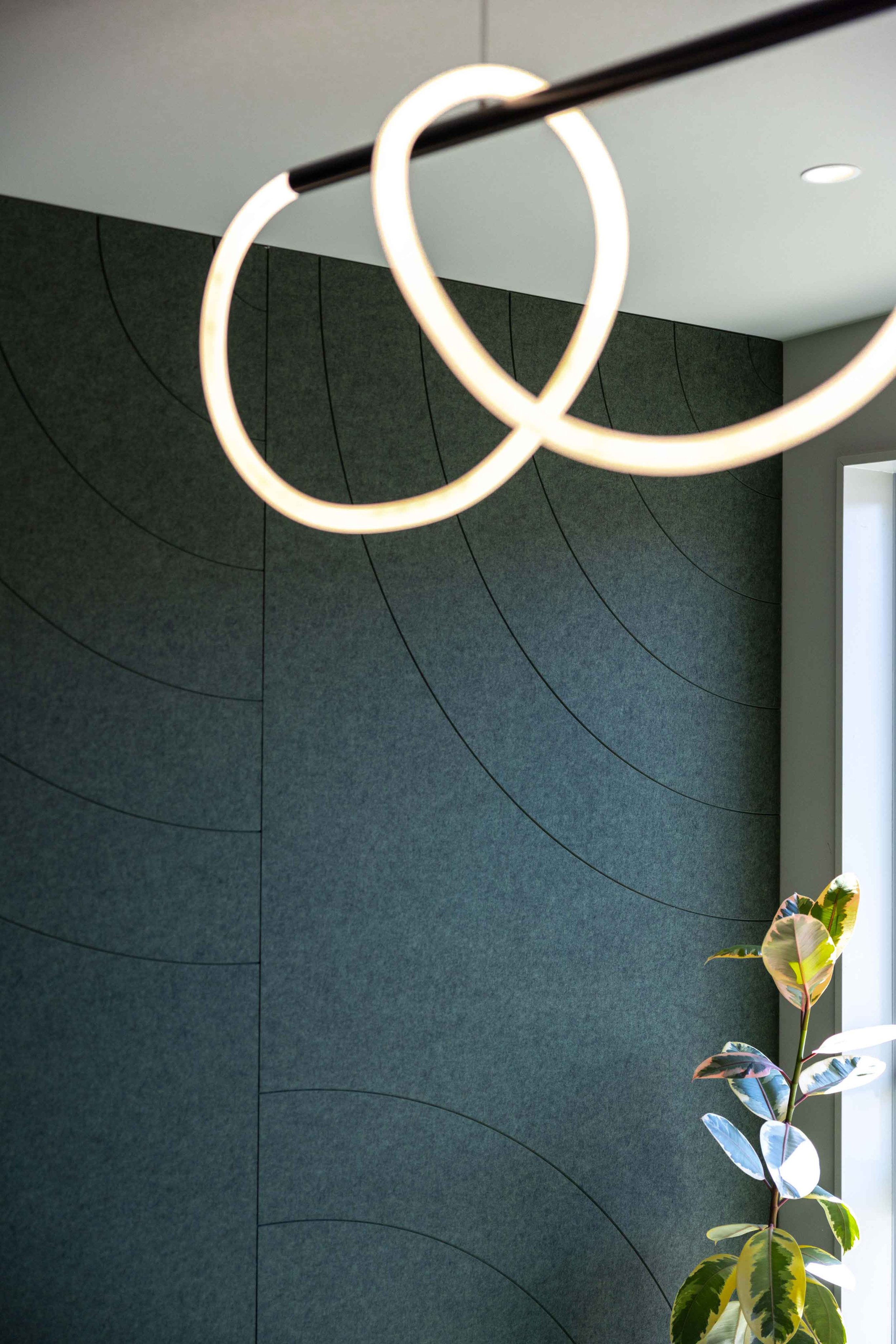 Modern interior with abstract circular wall decor, a circular LED light fixture, and a potted plant in a bright corner.