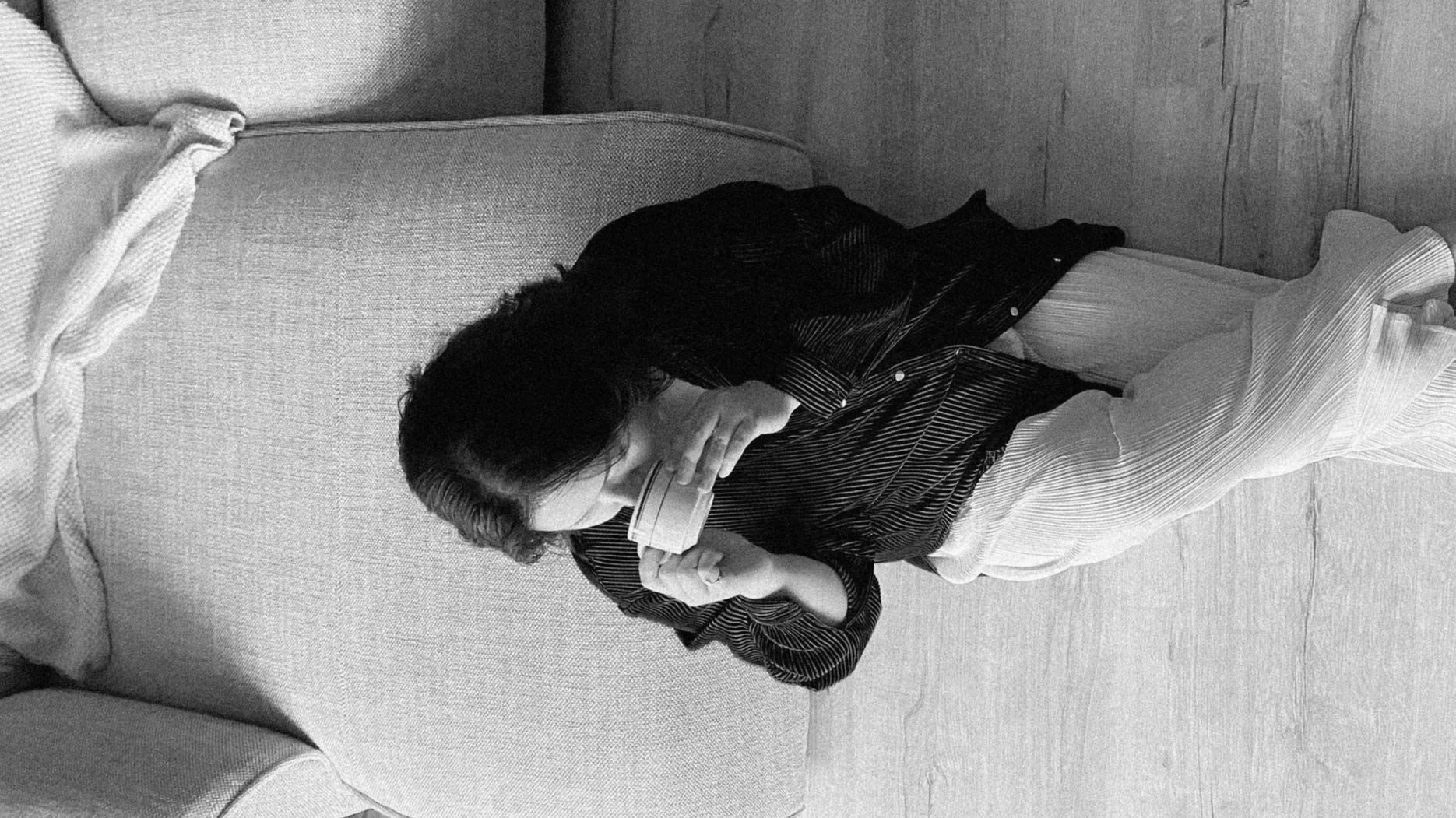 Nina sipping coffee sitting on the floor with her back against a sofa in black and white photo