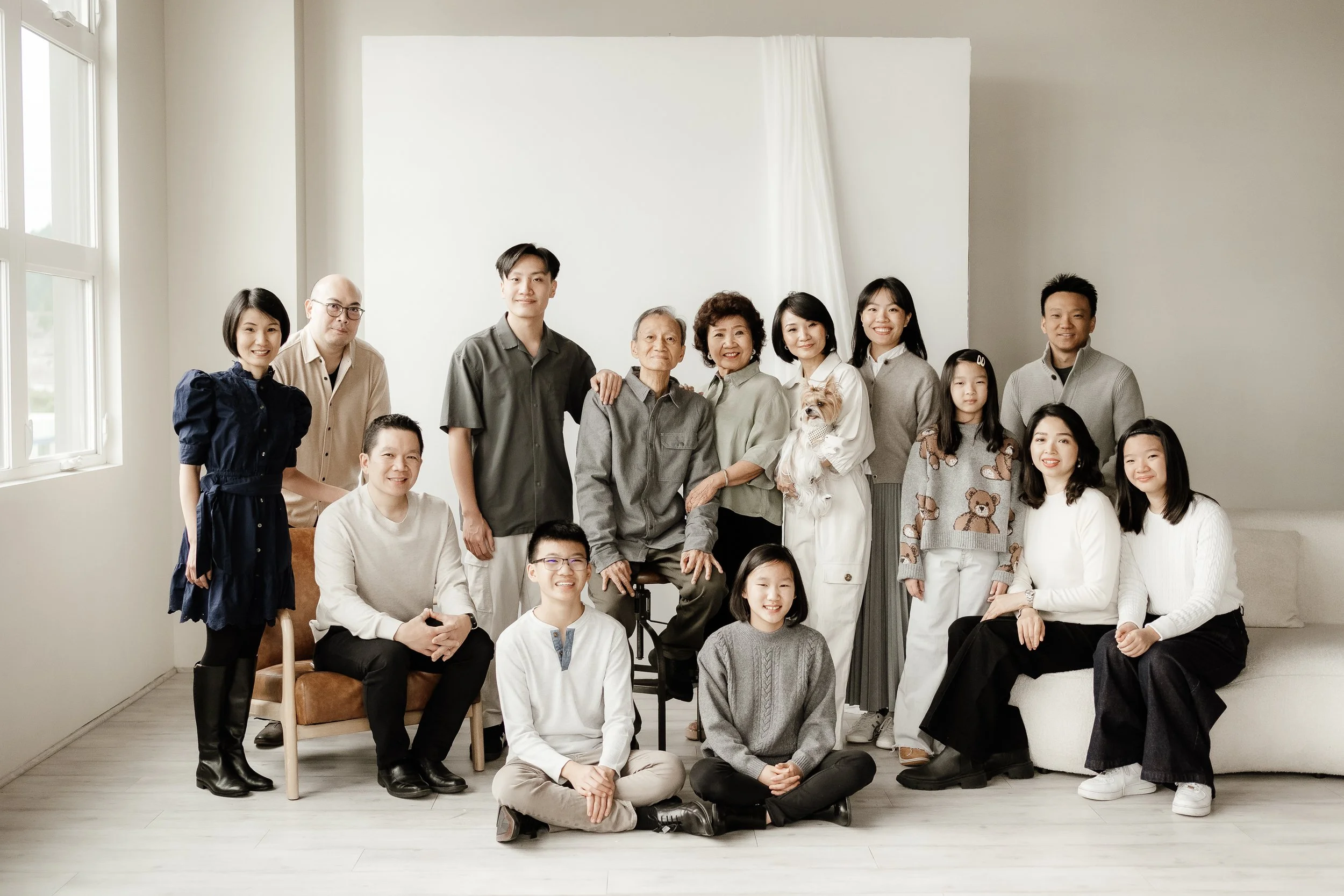 A large multi-generational Asian family gathering indoors, with members smiling and posing for a group photo.