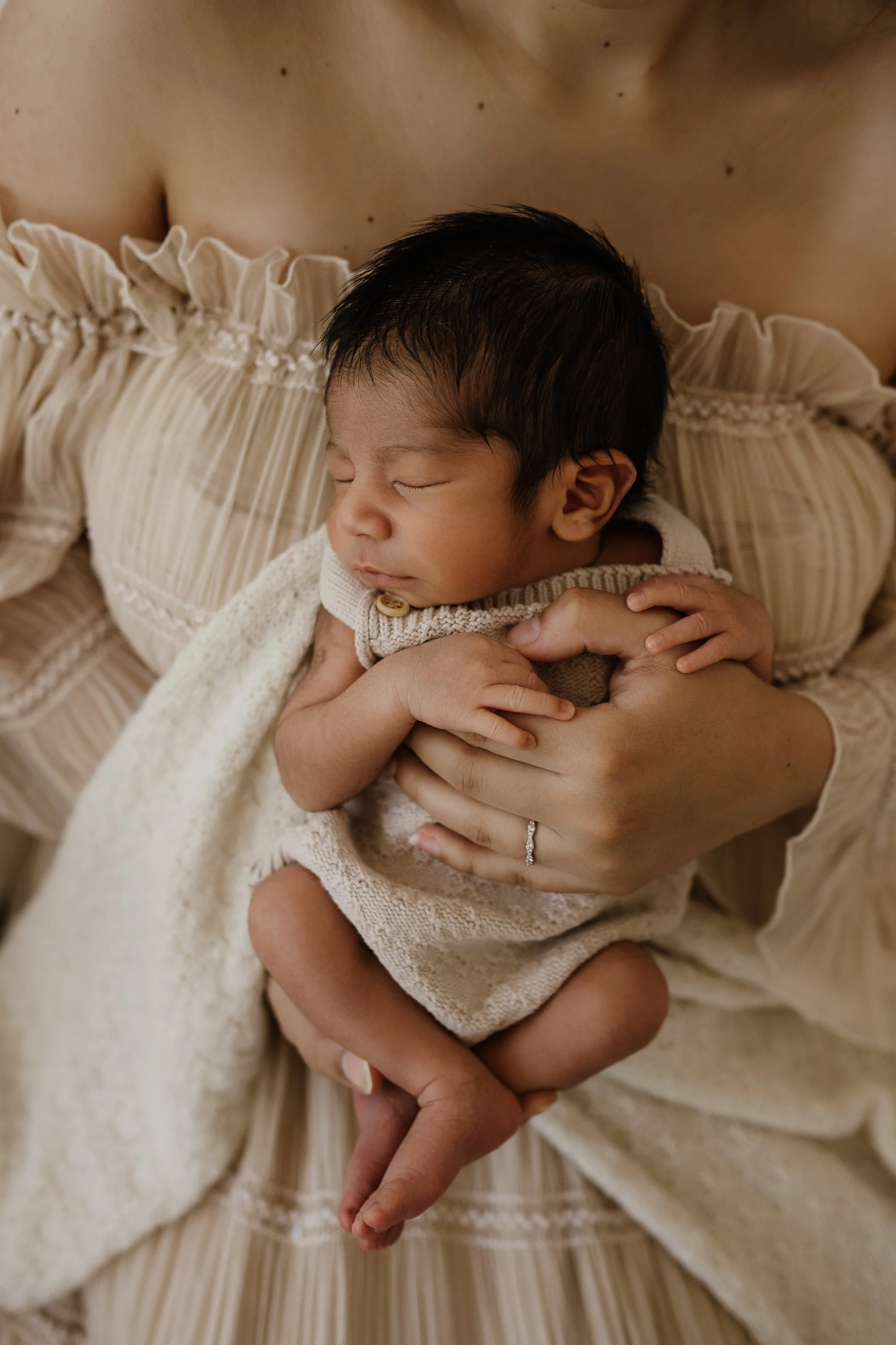 A newborn baby peacefully sleeping while being held by a woman.