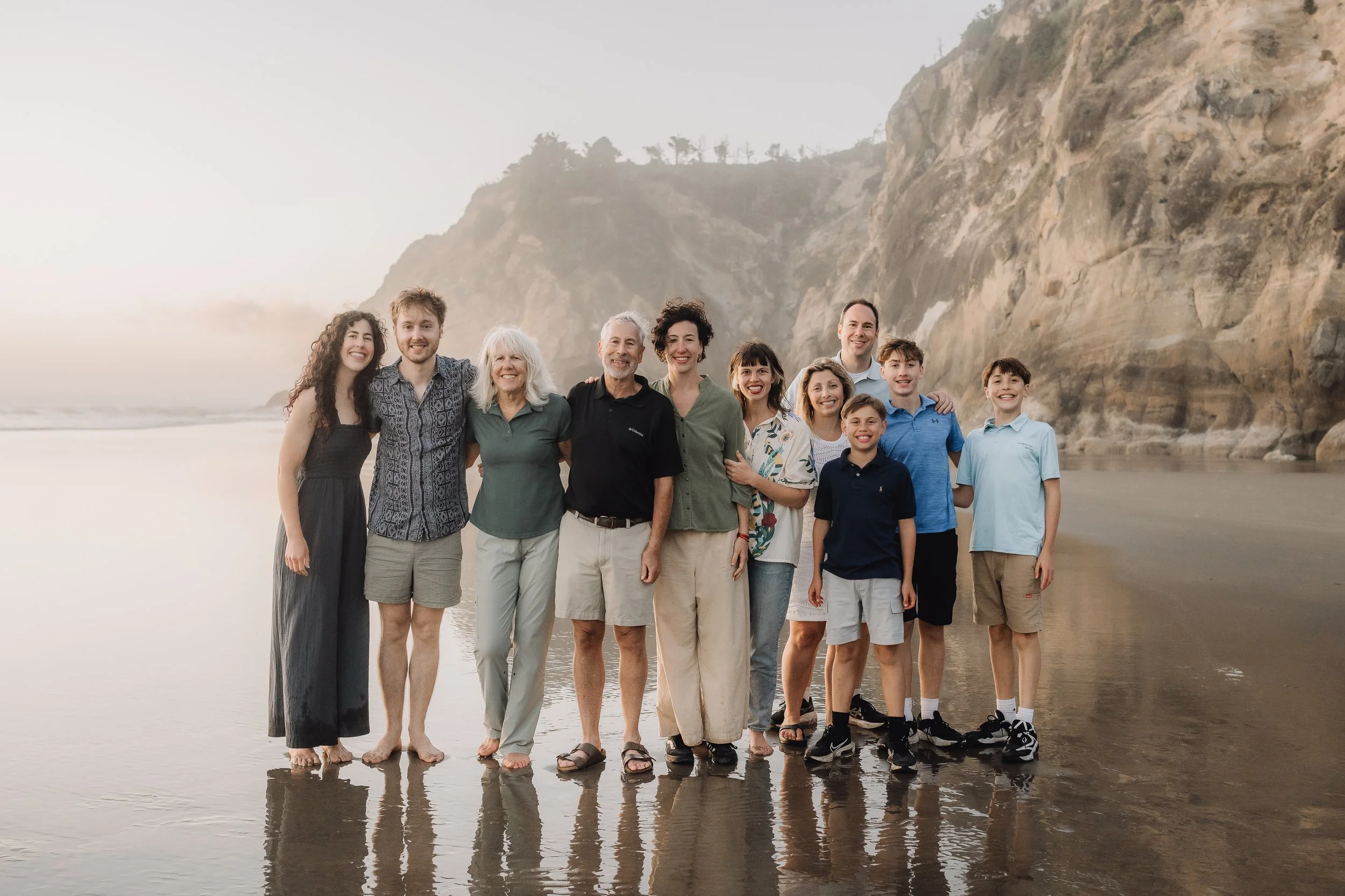 Family group standing on the beach with cliffs in the background.