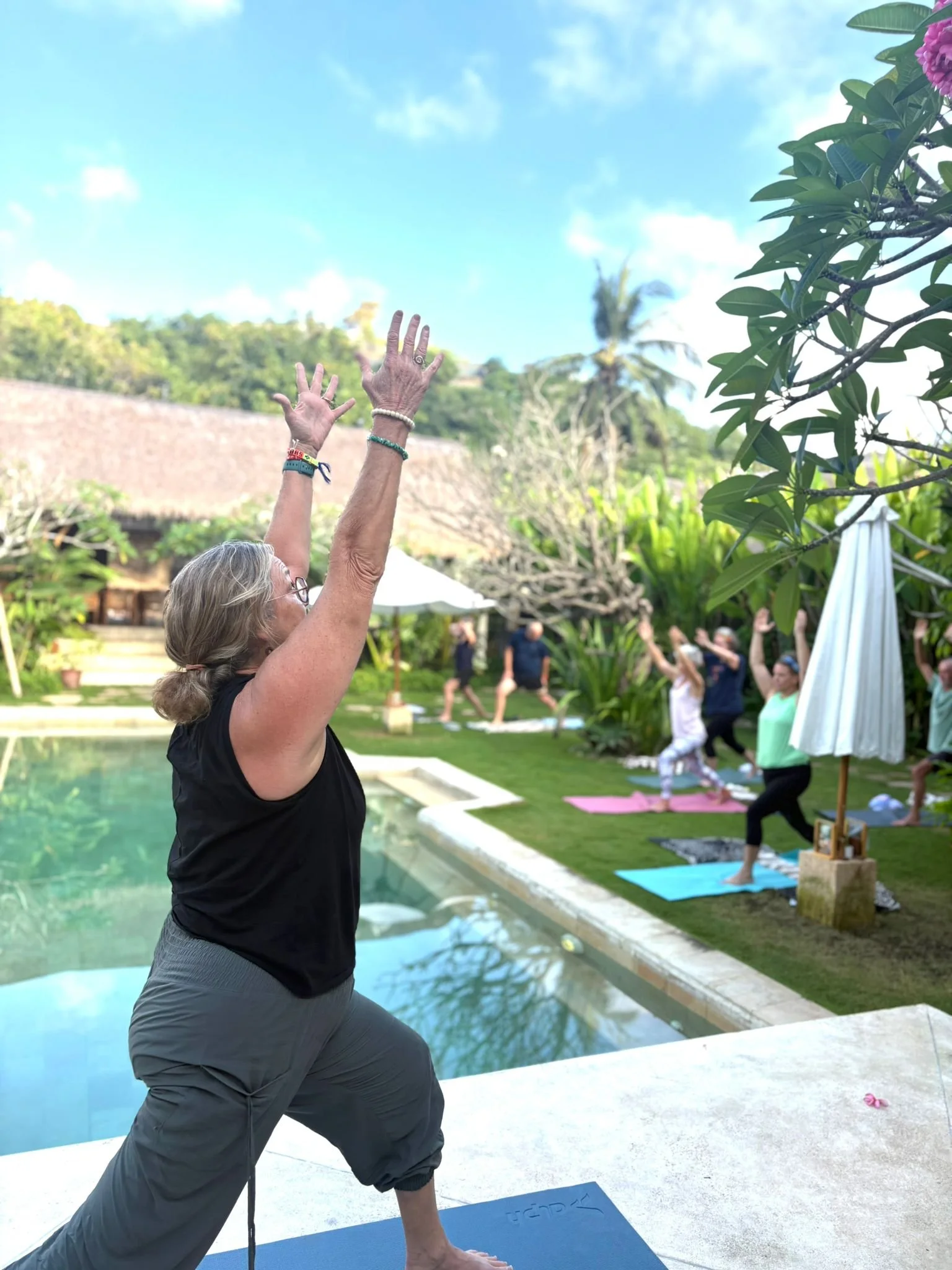 Poolside yoga class surrounded by tropical plants