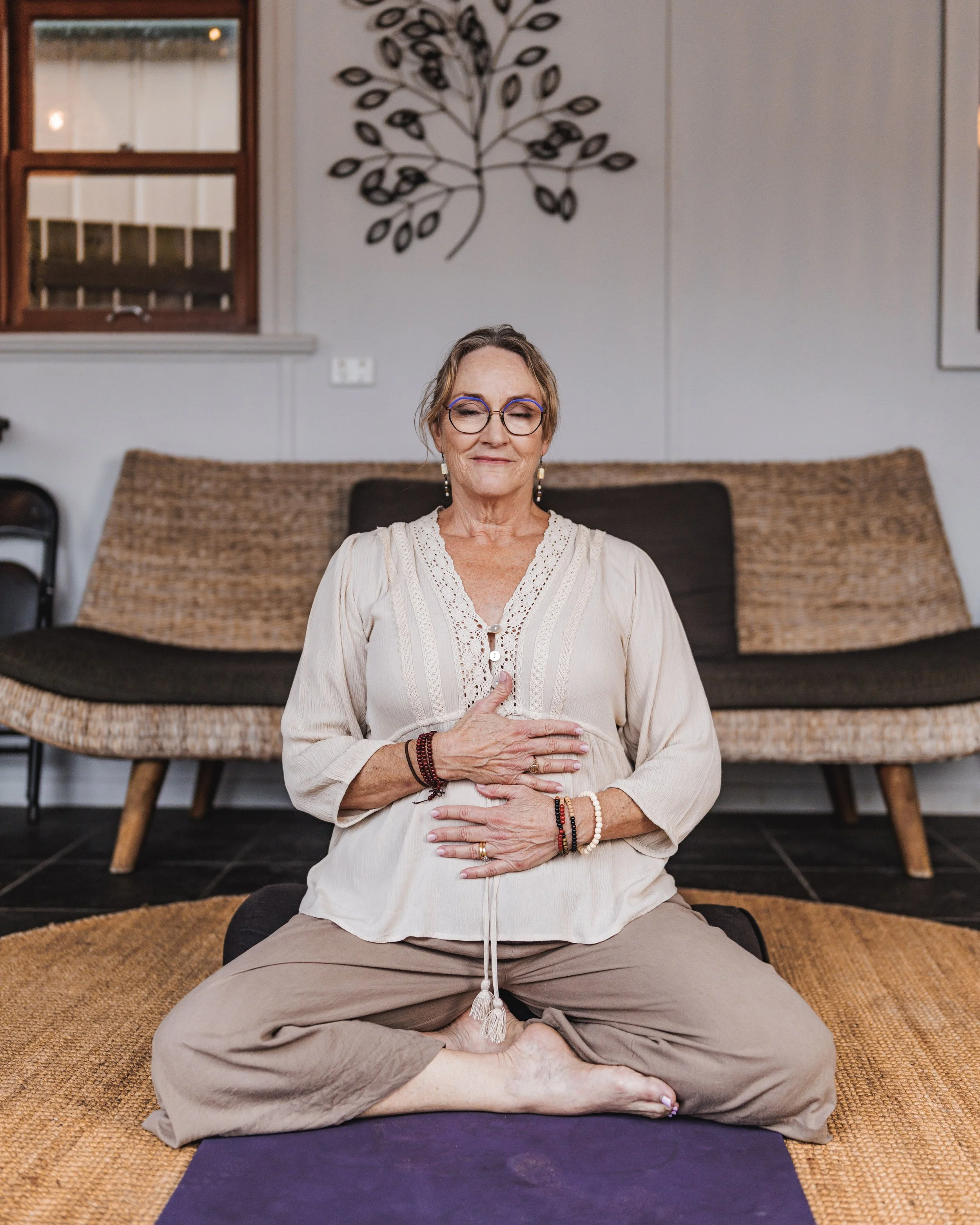 middle aged woman sitting on a yoga cushion meditating