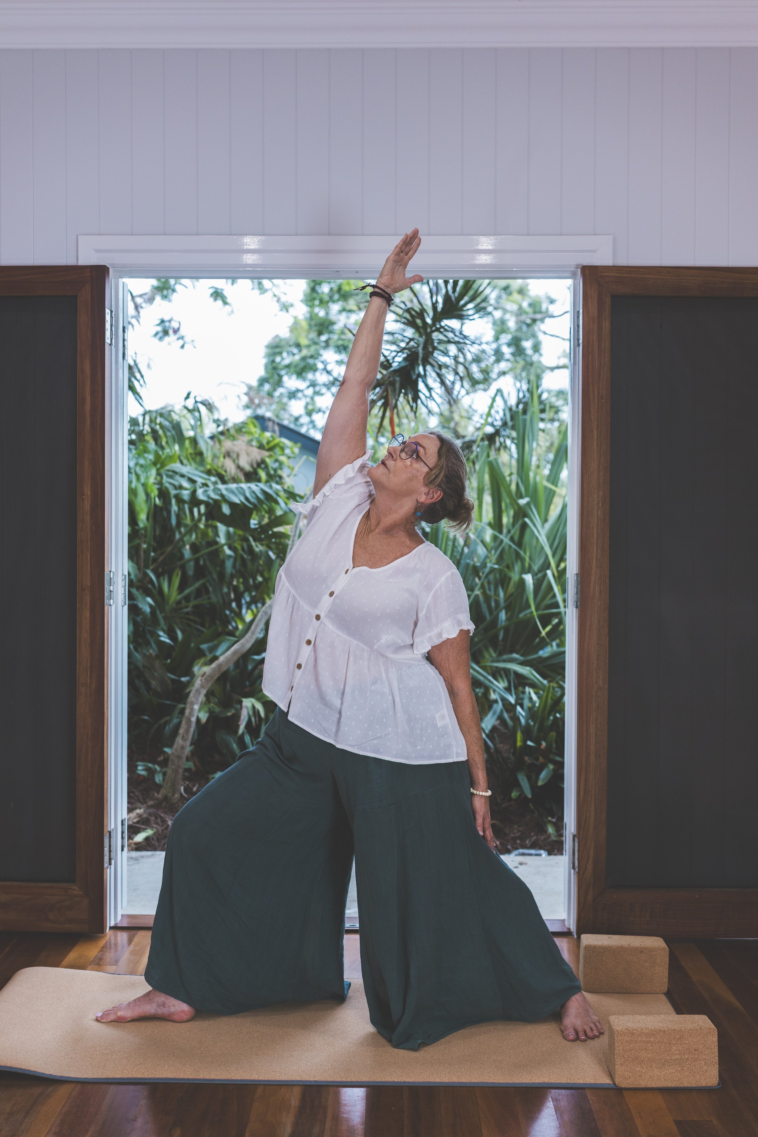 Shannon in standing yoga pose wearing flowing pants and top