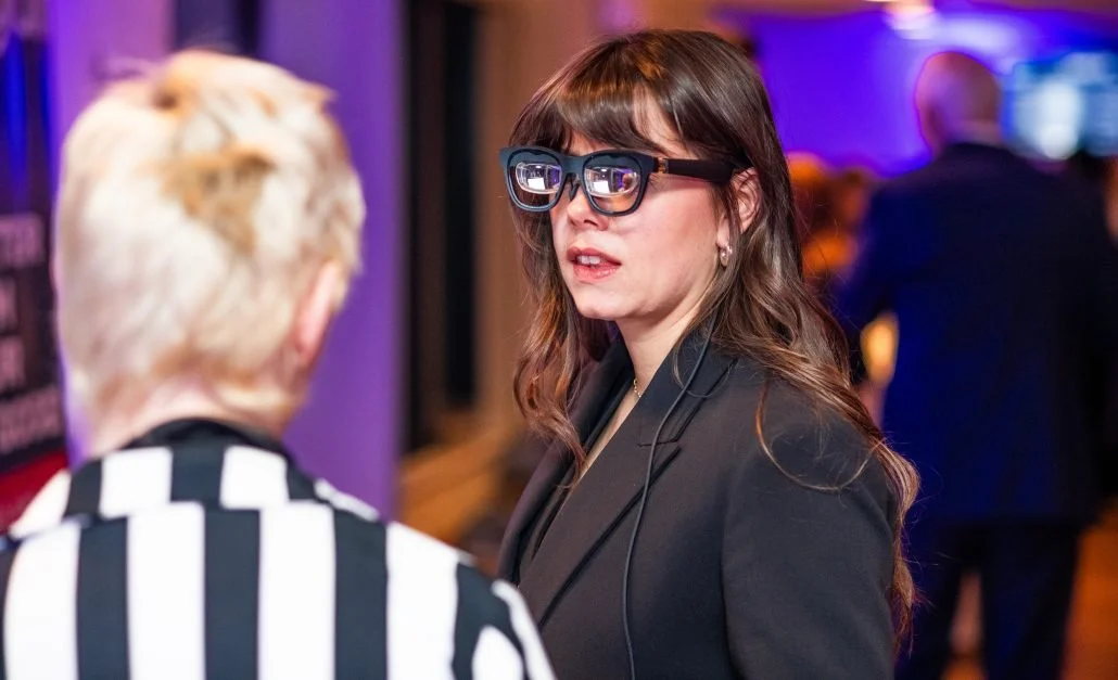 a close up of a woman with long dark hair wearing smart glasses