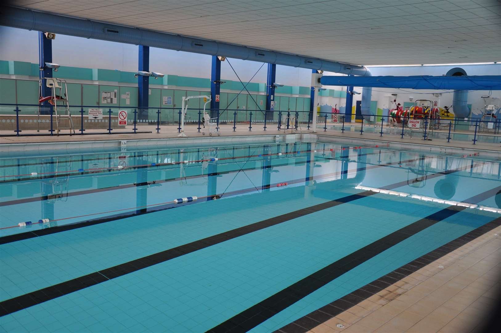 Indoor swimming pool with lane markers, safety equipment, and a slide at the far end.