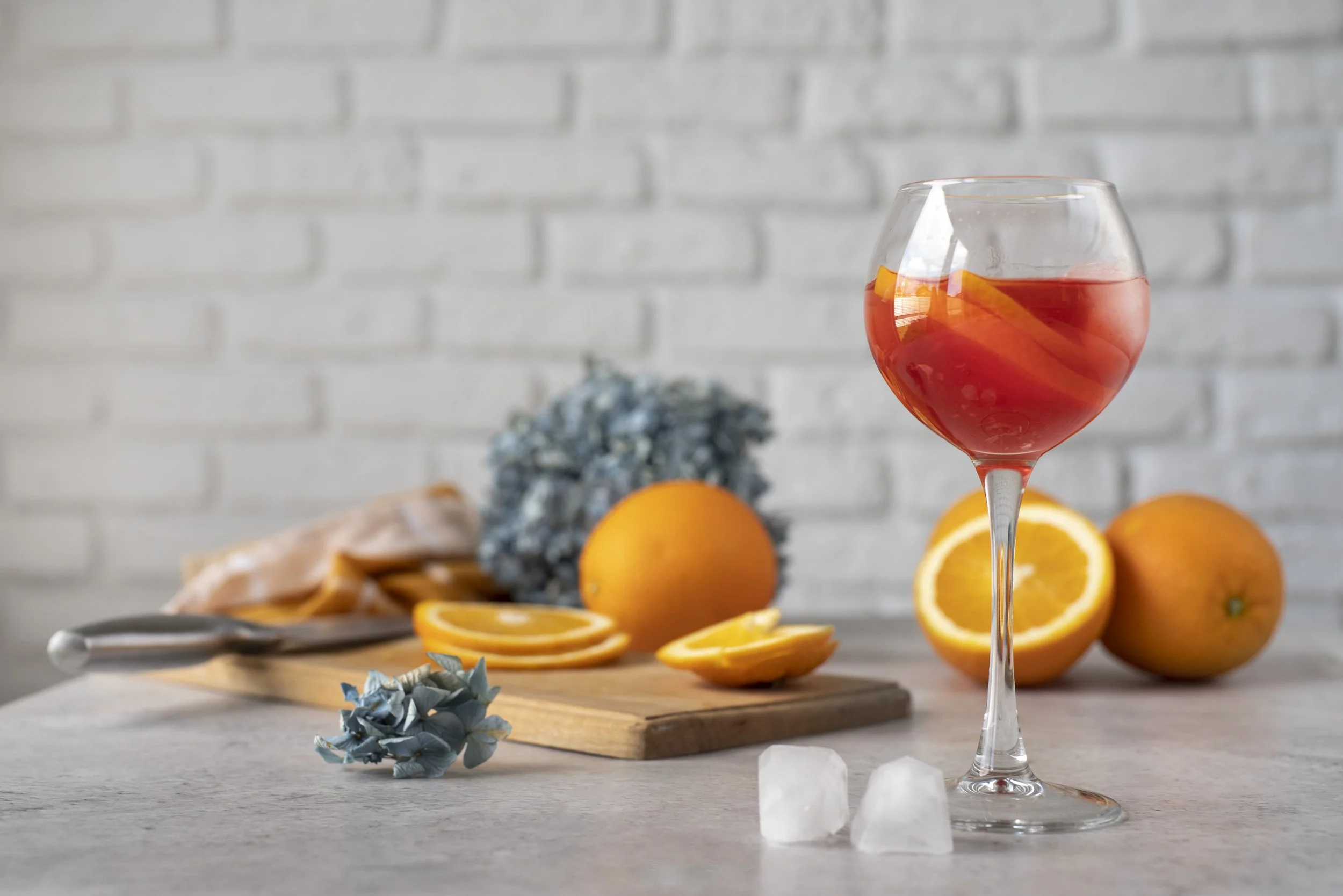 glass with orange drink and oranges on a kitchen table