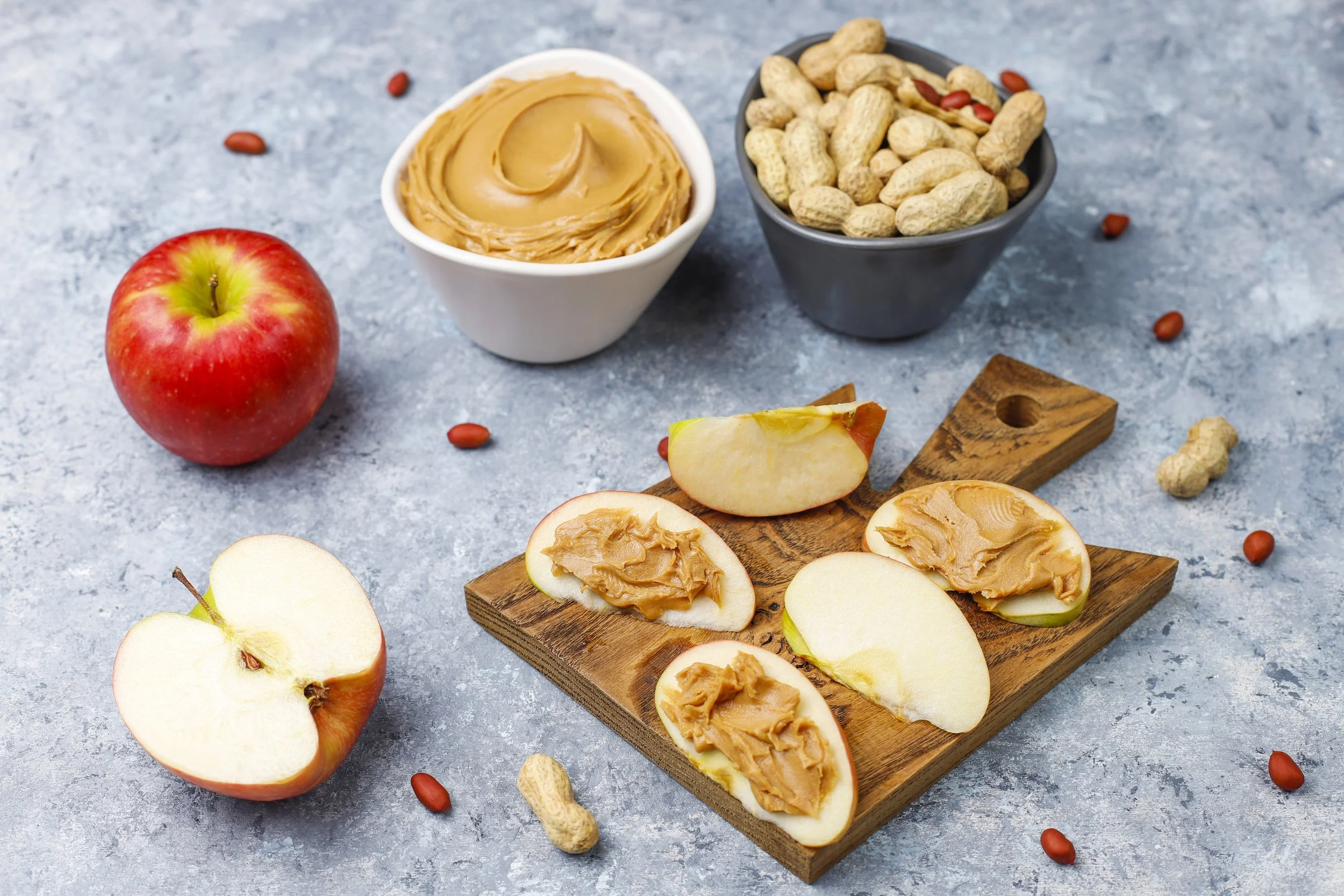 apple slices on a plate with nut butter and peanuts