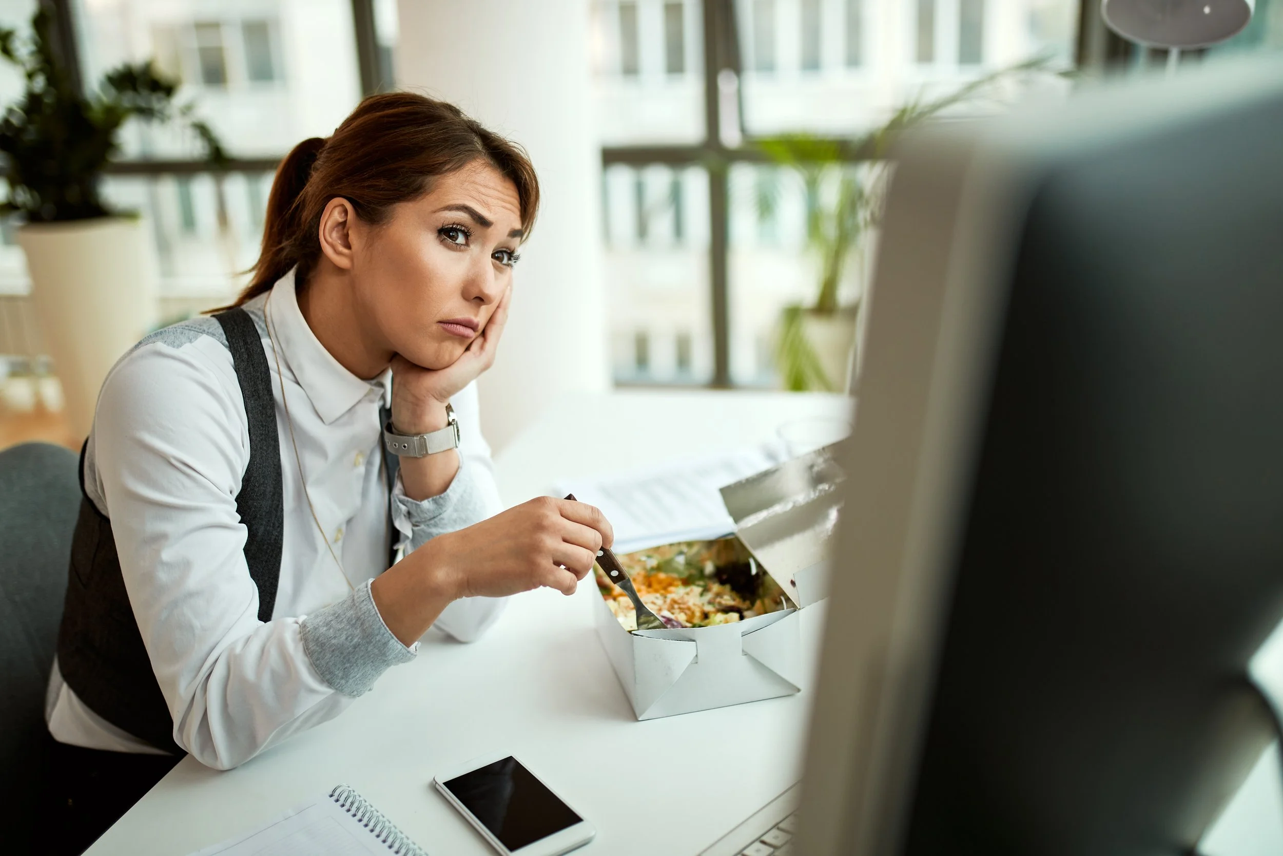 stressed woman eating in front of a computer