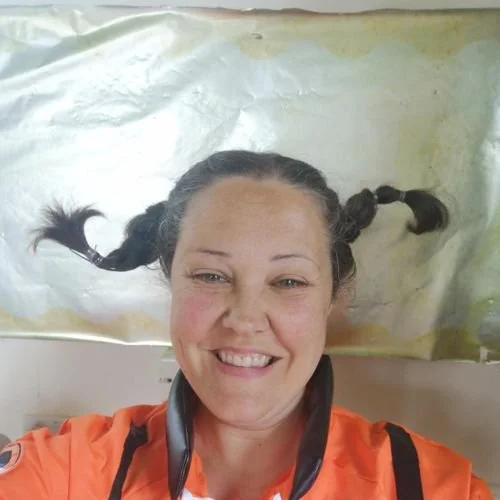 A woman with braided hair taking a selfie while lying down, with her head on a paper-covered surface.