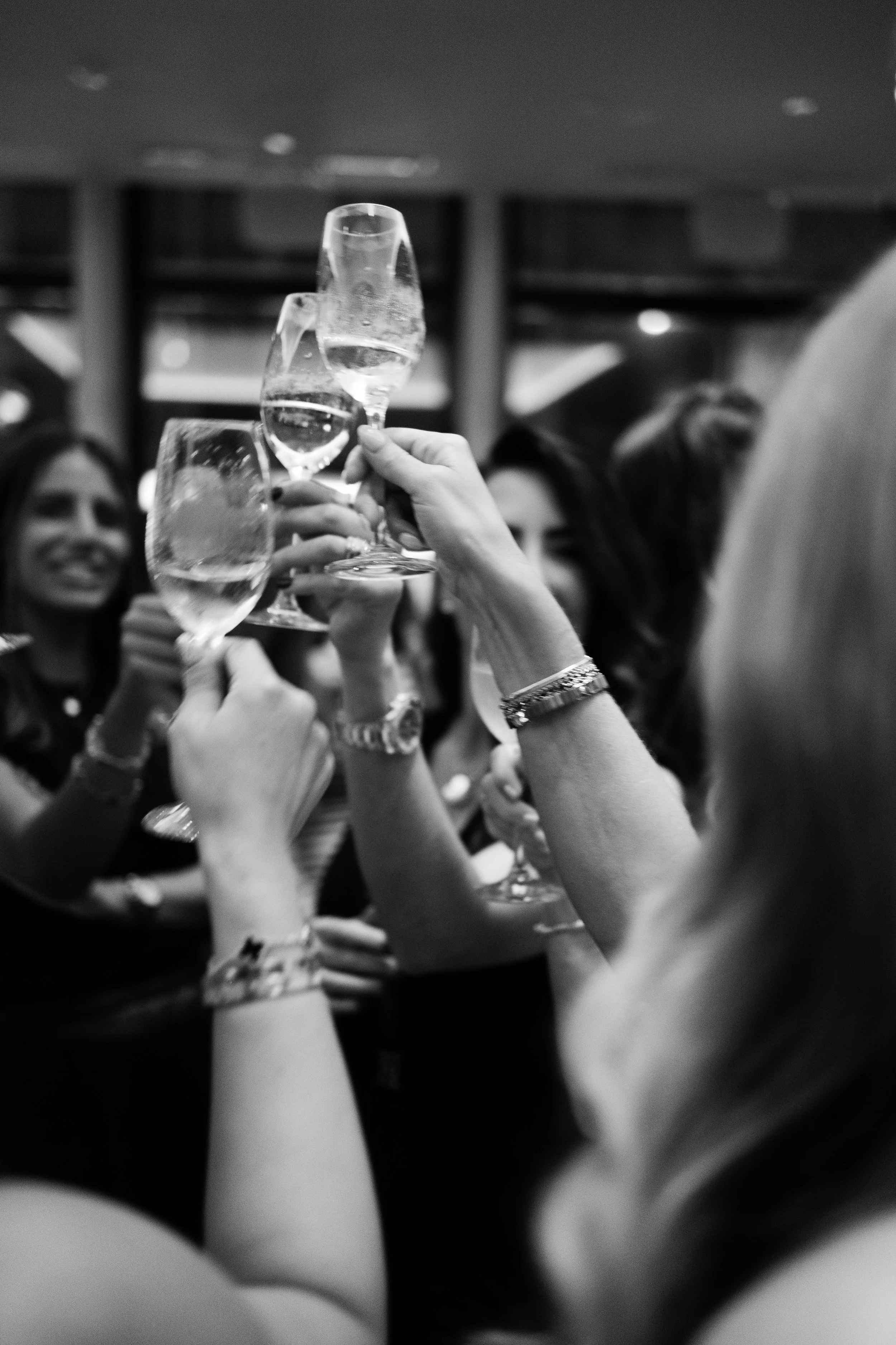 Group of women raising glasses of champagne in celebration at a social gathering.