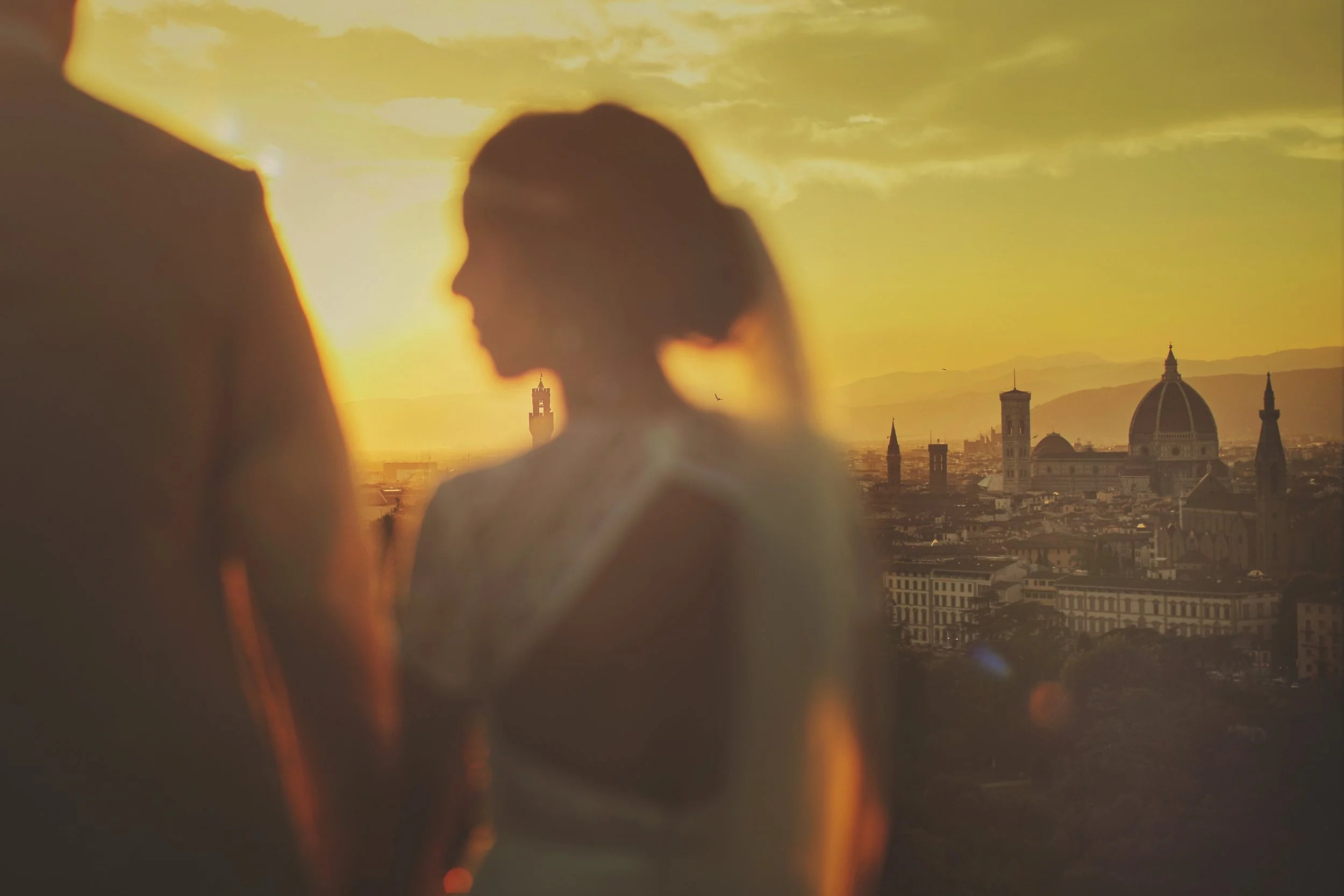 Silhouette of a couple with the Florence skyline, featuring the Duomo, at sunset.