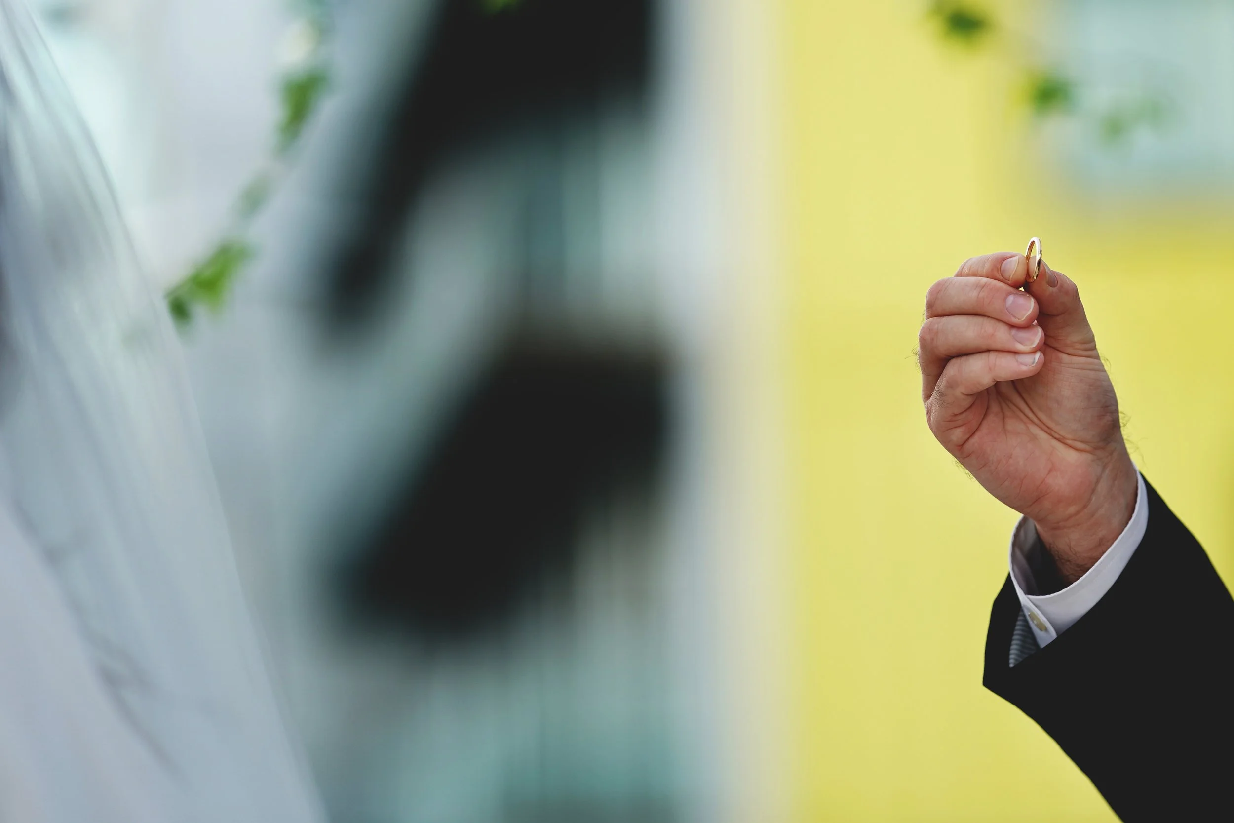 Person holding a wedding ring outdoors.