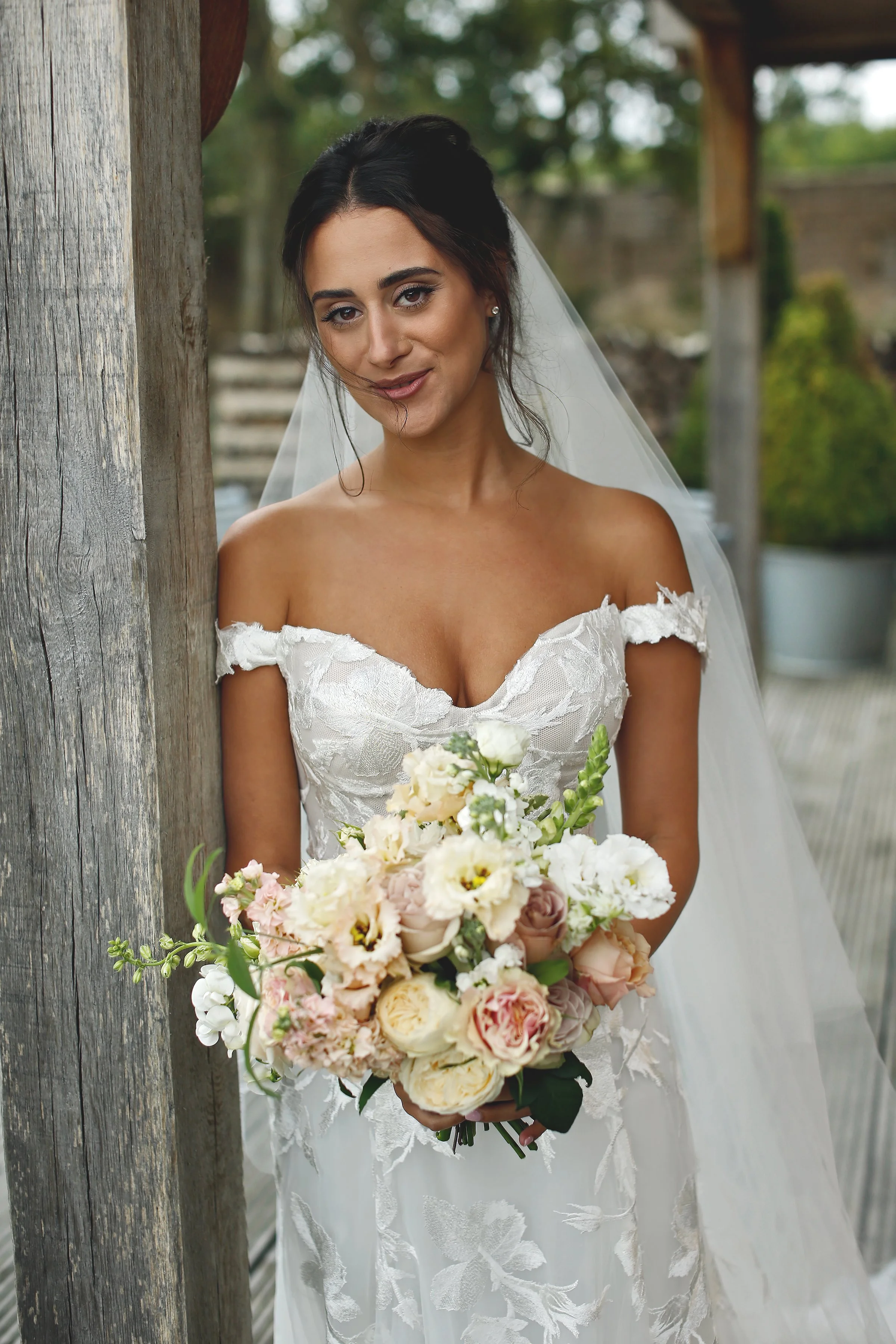 Bride in lace dress holding a bouquet of flowers.