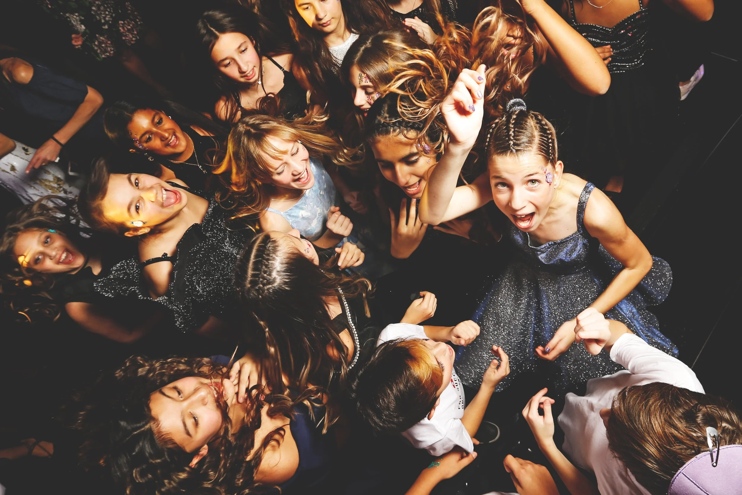 Group of young people dancing at a party, wearing festive clothing, with joyful expressions.