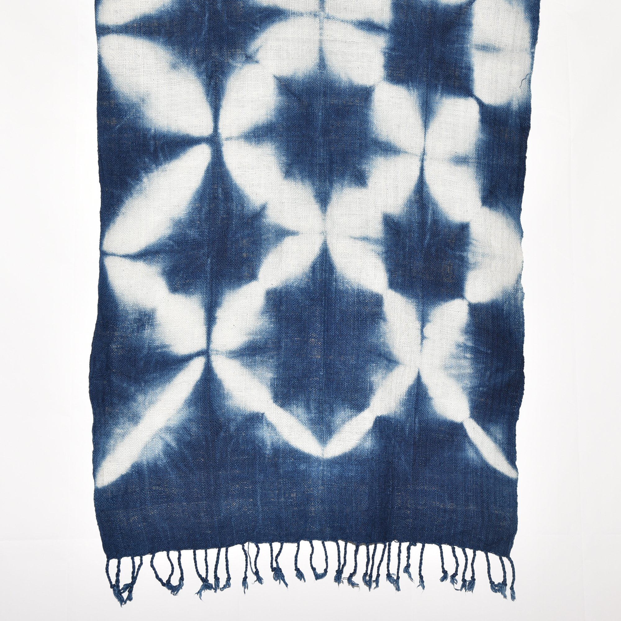 Handspun, hand-dyed, and hand-woven indigo and white tie-dyed shawl made from thick organic cotton with tassels. Measures 2 meters by 70 centimeters.