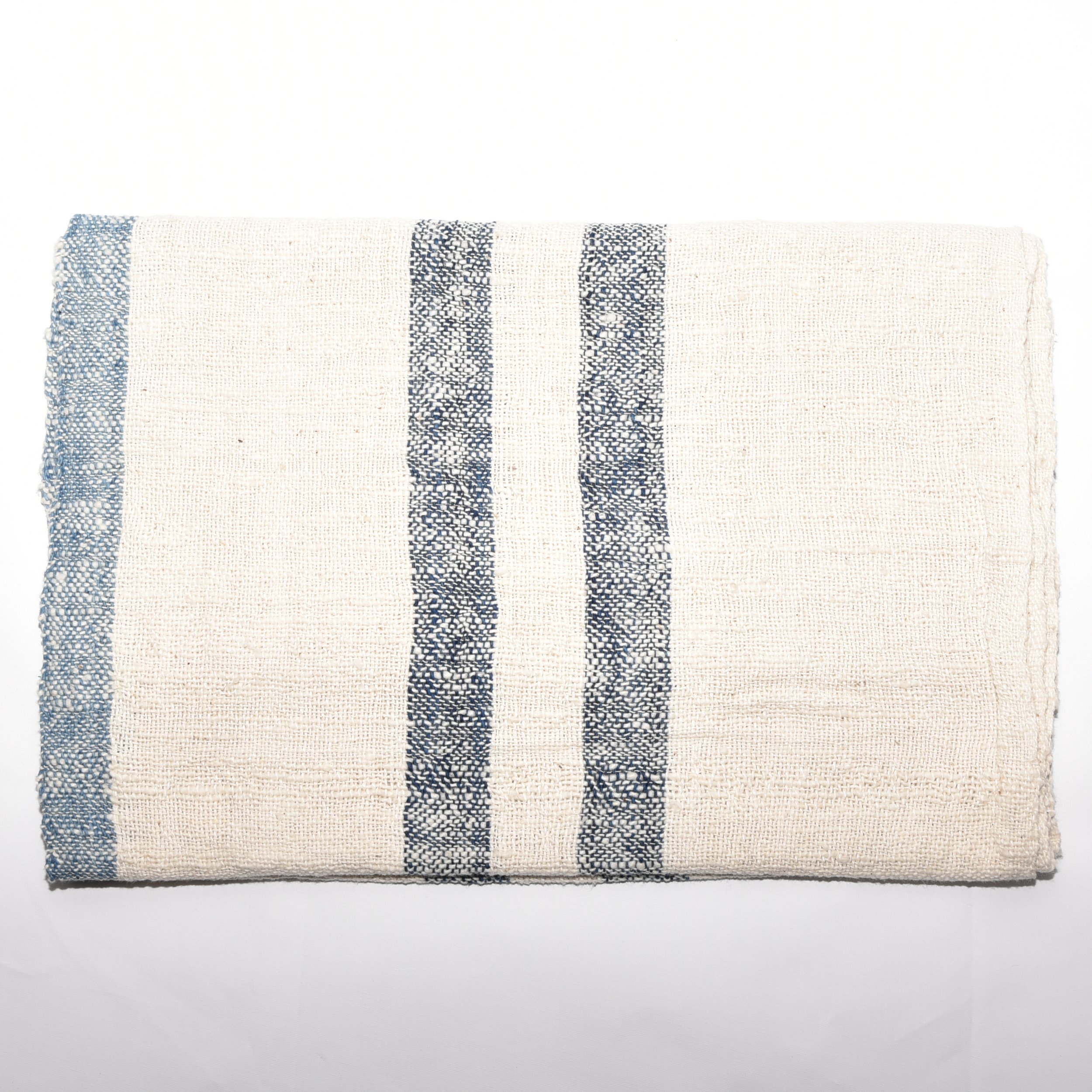 A long, striped scarf made from thick, organic cotton. The stripes are in shades of indigo and white. The scarf is hand-spun, hand-dyed, and hand-woven, with tassels at each end.