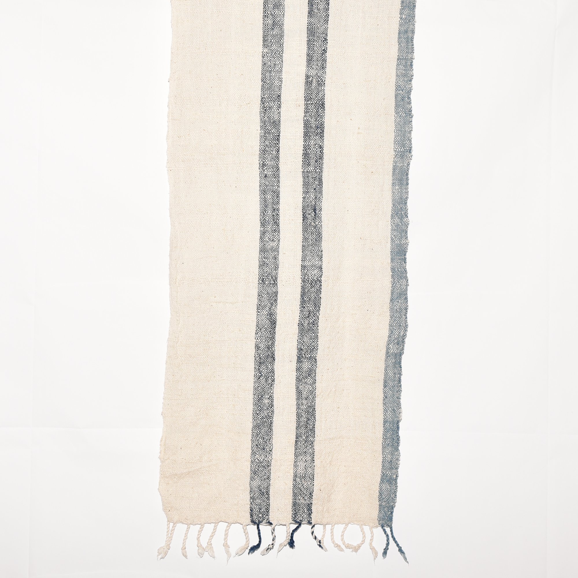 A long, striped scarf made from thick, organic cotton. The stripes are in shades of indigo and white. The scarf is hand-spun, hand-dyed, and hand-woven, with tassels at each end.
