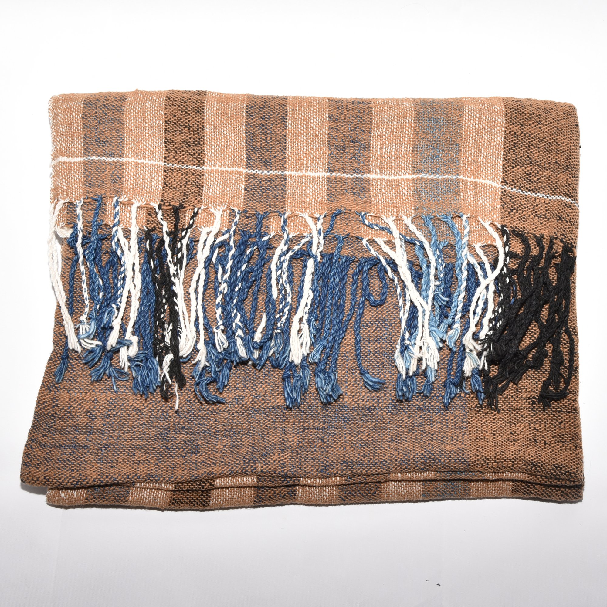 Hand-spun, hand-dyed, and hand-woven shawl made from thick organic cotton, featuring stripes in brown, tan, indigo, black, and white, with tassels at both ends. The shawl measures 2m x 70cm.