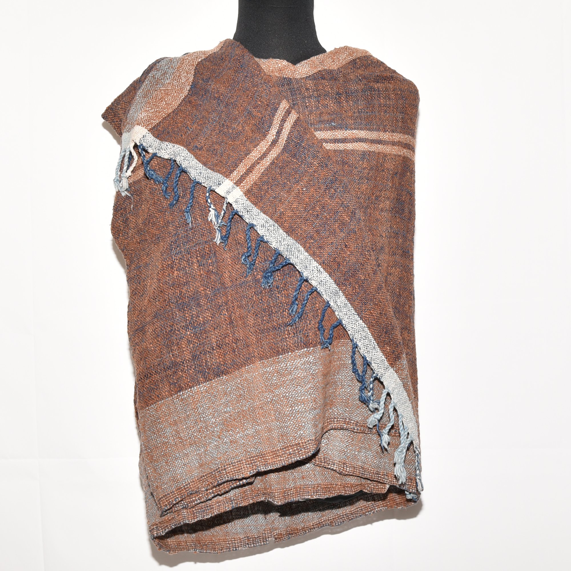 A luxurious, hand-woven shawl made from thick organic cotton. Featuring bold stripes in brown, tan, indigo, and white, it's finished with tassels.