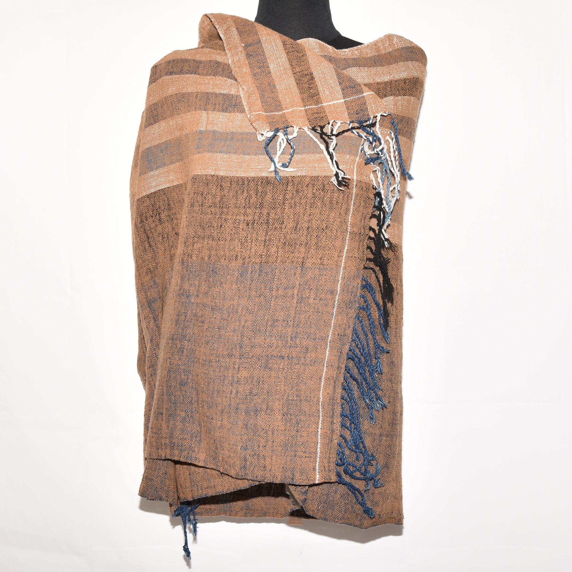 Hand-spun, hand-dyed, and hand-woven shawl made from thick organic cotton, featuring stripes in brown, tan, indigo, black, and white, with tassels at both ends. The shawl measures 2m x 70cm.