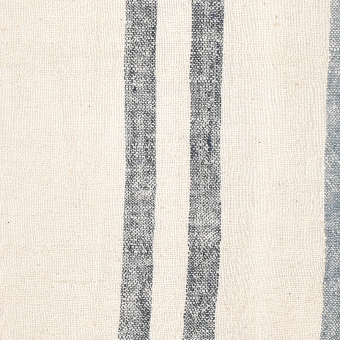 A long, striped scarf made from thick, organic cotton. The stripes are in shades of indigo and white. The scarf is hand-spun, hand-dyed, and hand-woven, with tassels at each end.