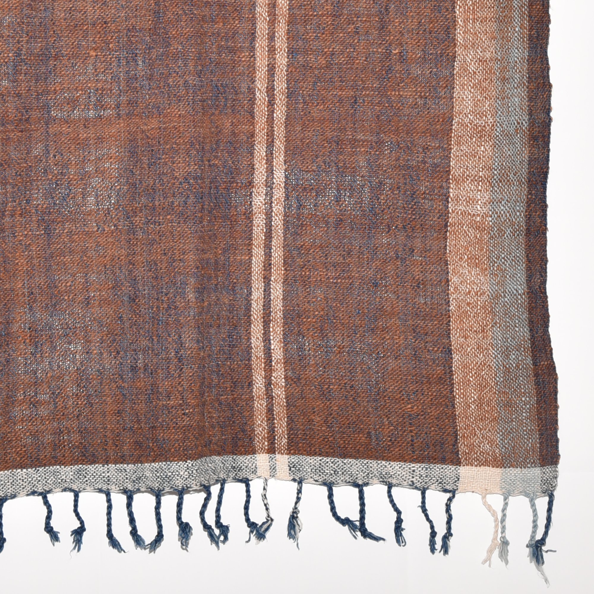 A luxurious, hand-woven shawl made from thick organic cotton. Featuring bold stripes in brown, tan, indigo, and white, it's finished with tassels.