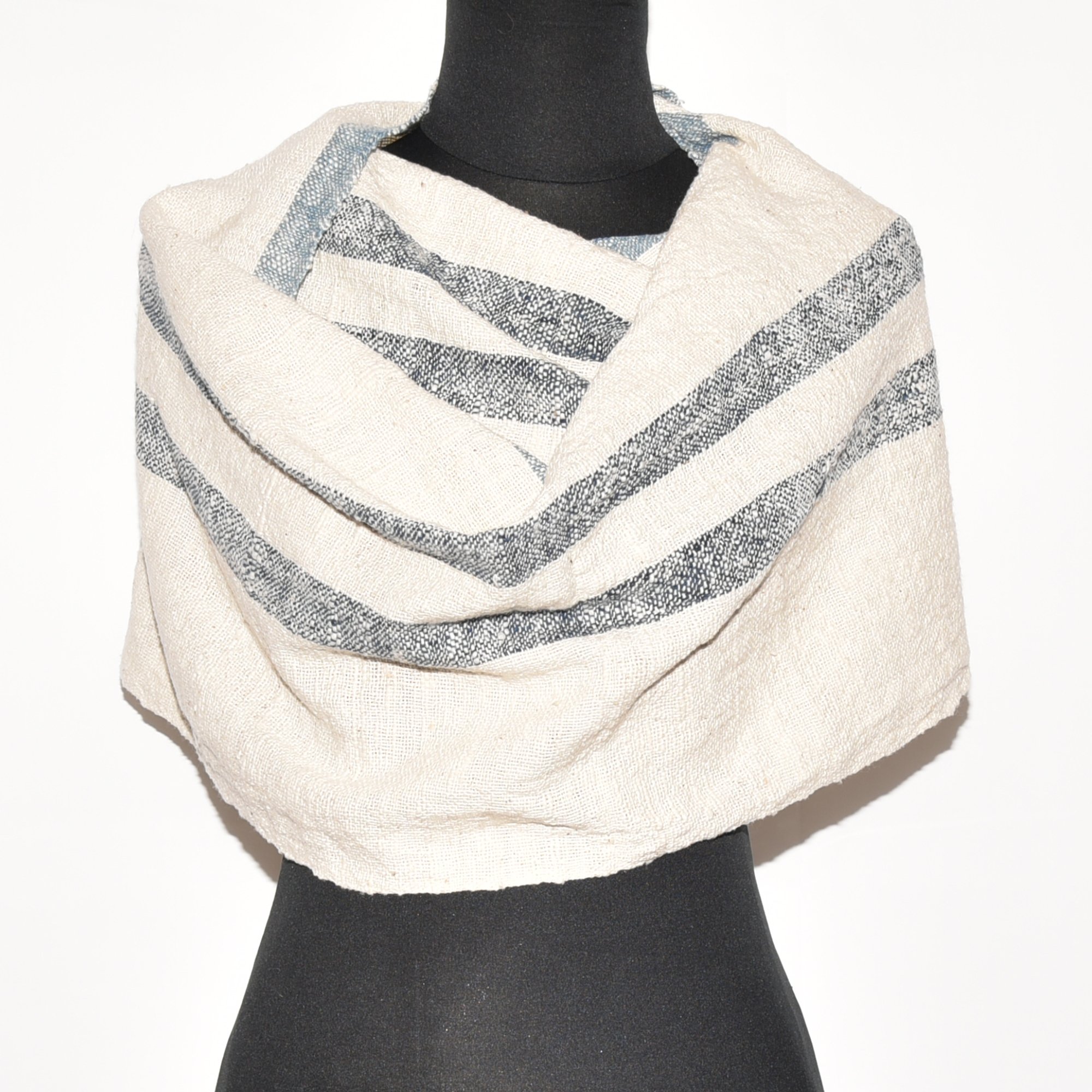 A long, striped scarf made from thick, organic cotton. The stripes are in shades of indigo and white. The scarf is hand-spun, hand-dyed, and hand-woven, with tassels at each end.