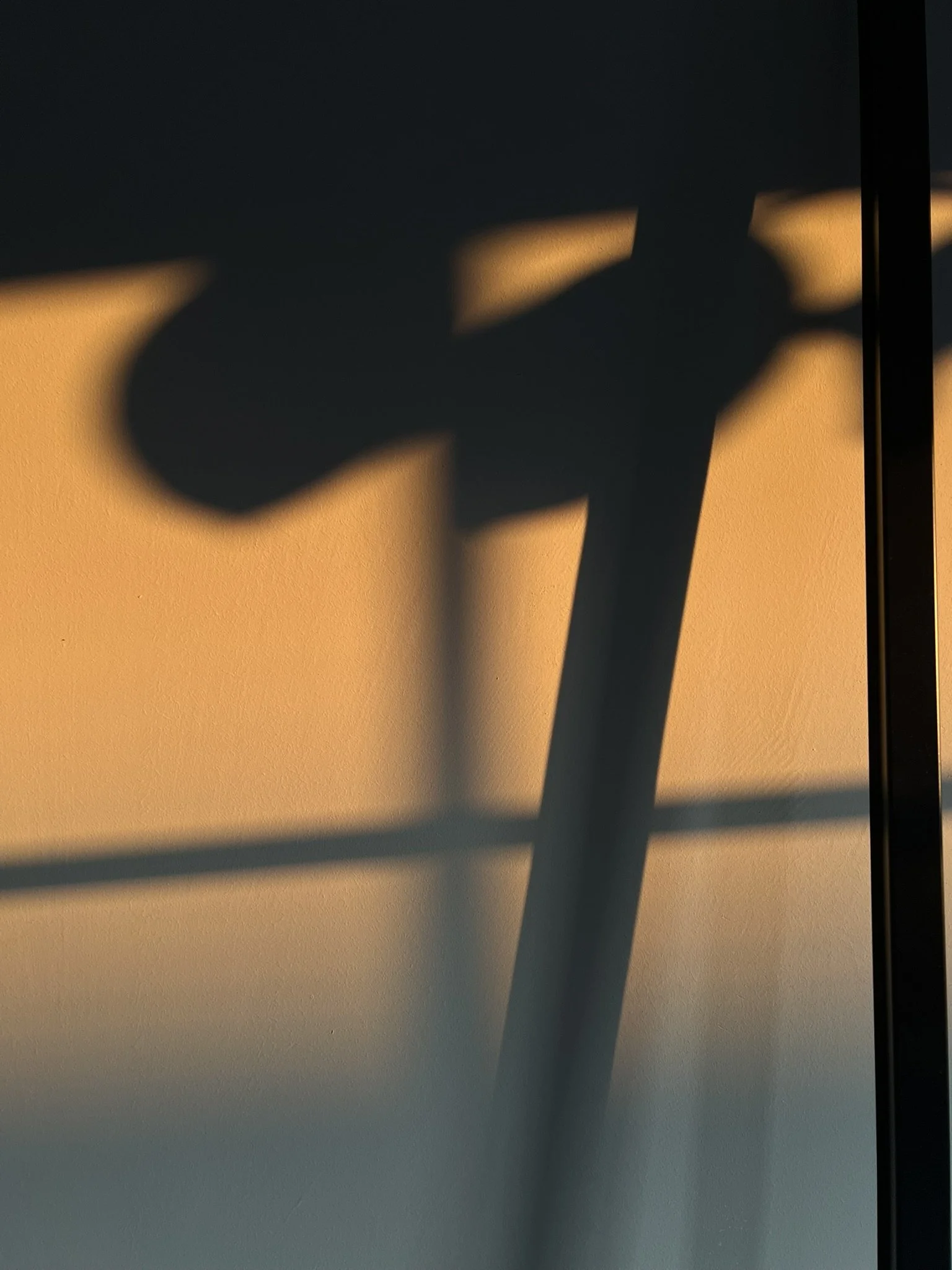 Schatten einer Wasserpumpe an einer Wand bei Sonnenuntergang