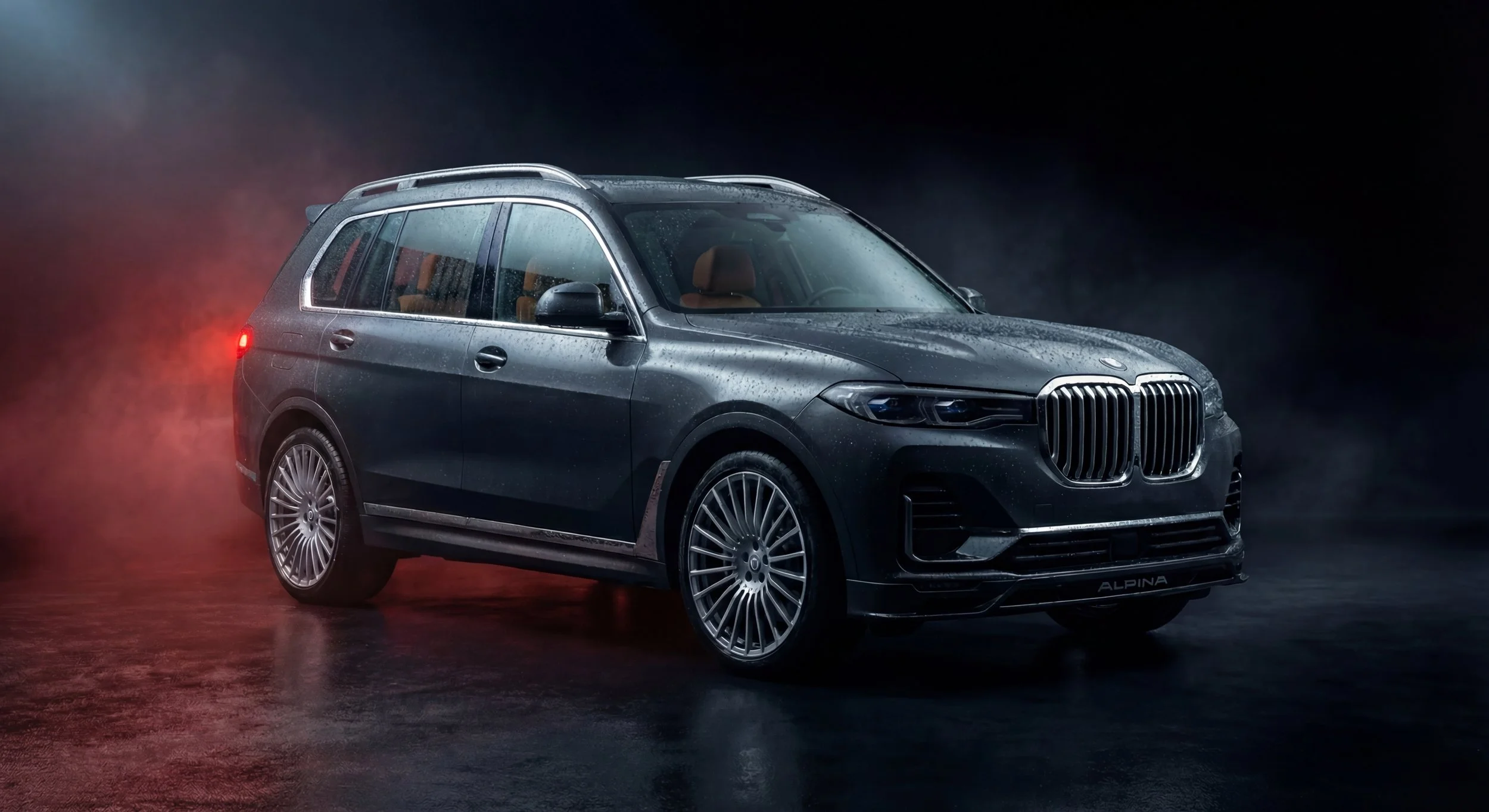 A dark grey Alpina XB7 with rain droplets, set against a black background with mist and red lighting effects.