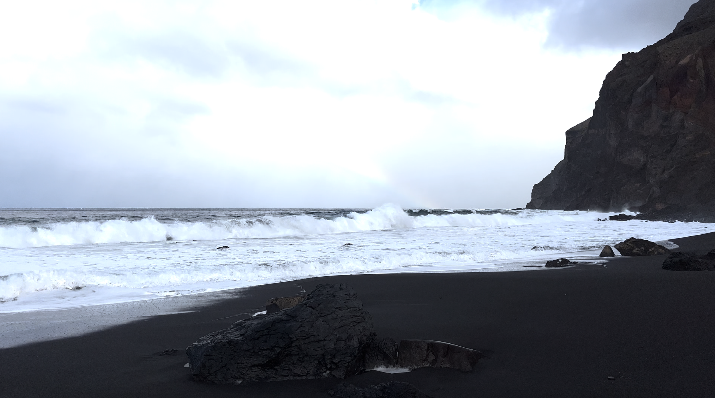 Waves crashing on a beach as a rainbow forms