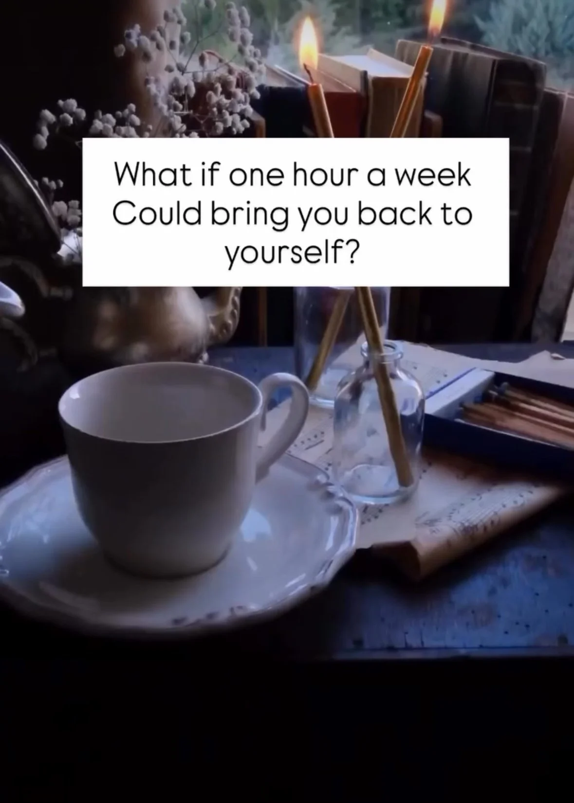 A cozy scene with a white cup on a matching saucer, surrounded by lit candles in a glass holder, dried flowers, and books on a table bathed in soft natural light. The text overlay reads: "What if one hour a week could bring you back to yourself?"