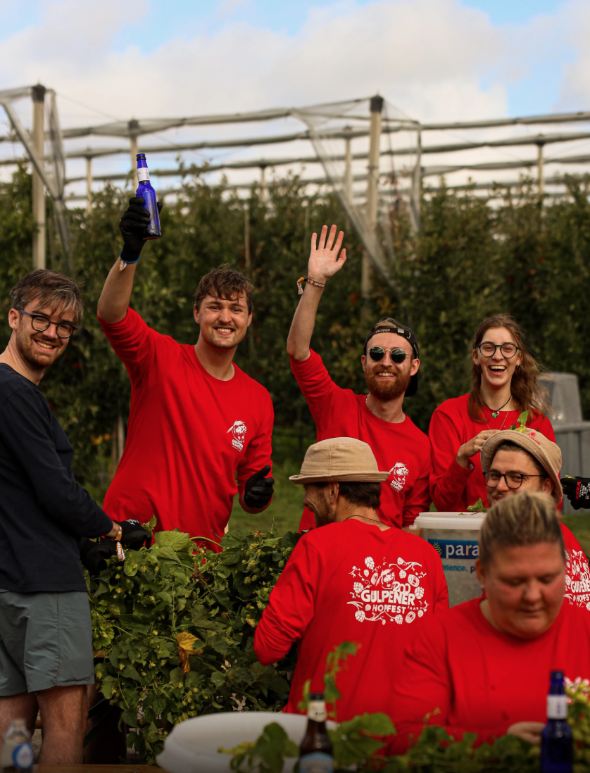 Groep mensen in rode Gulpener sweaters vieren samen op een buiten brand event — live merkbeleving vastgelegd door Stronger Stories