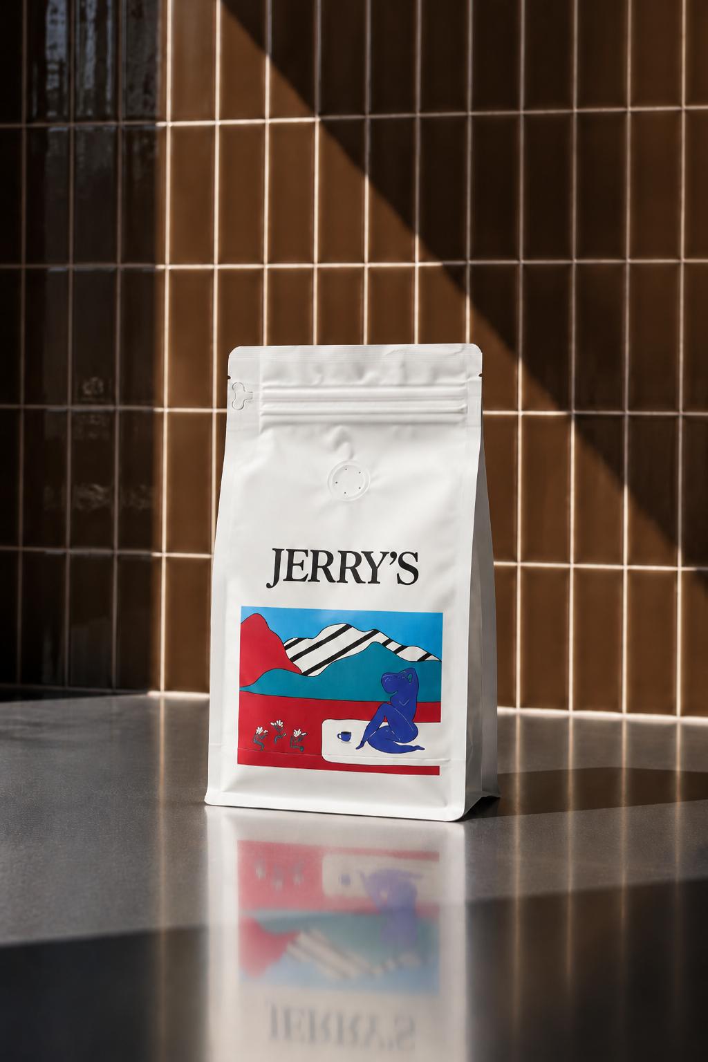 A white package of Jerry's coffee with a colorful mountain and bear illustration standing on a gray countertop.