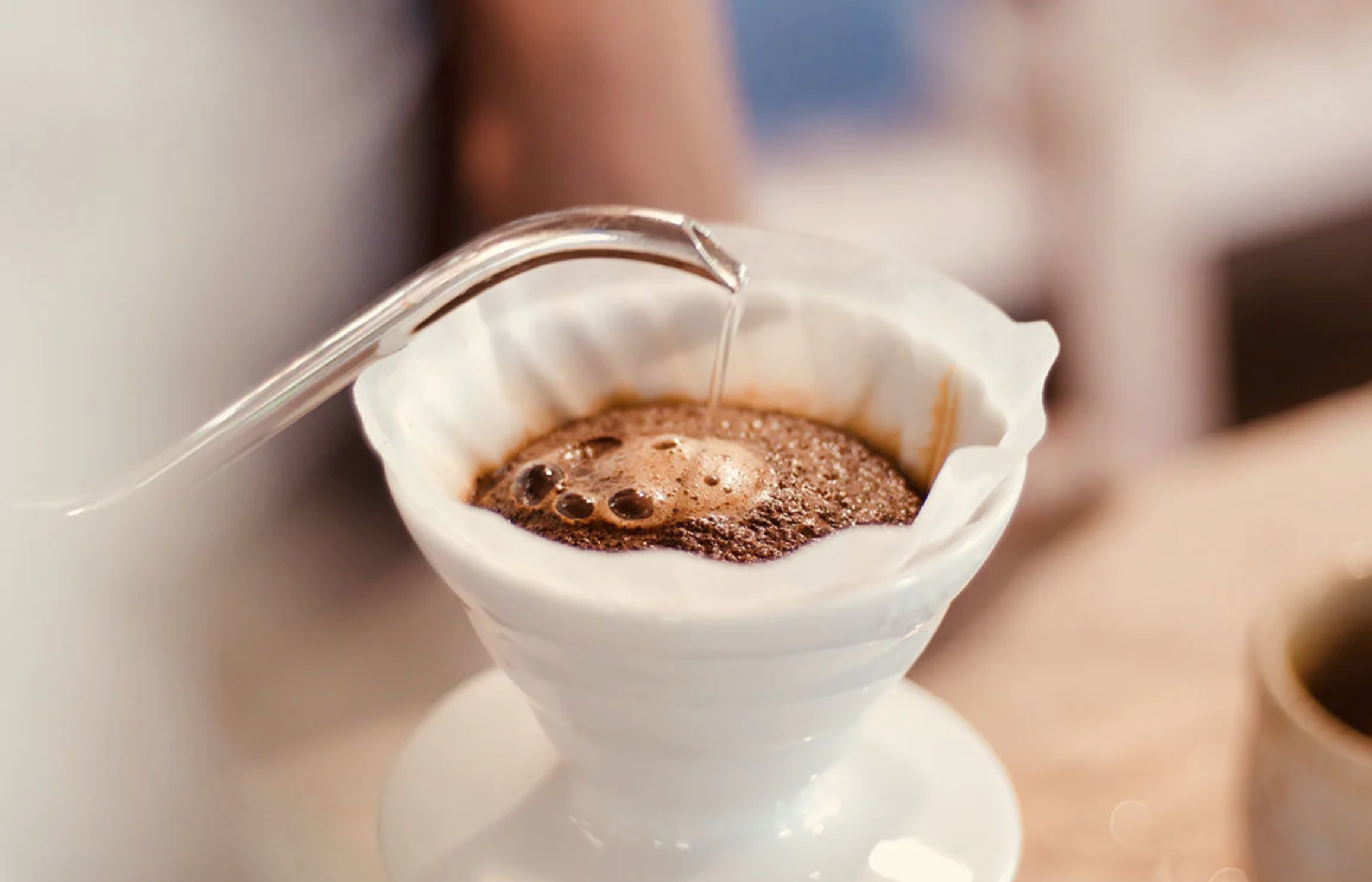 Pouring hot water into a coffee dripper filled with coffee grounds for brewing.
