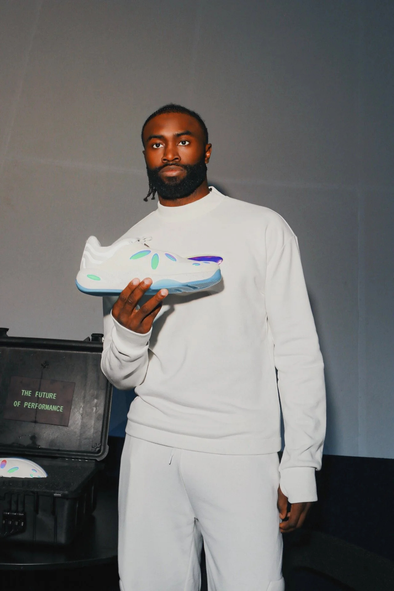 Jaylen Brown holding his  futuristic sneaker next to a case labeled "The Future of Performance."