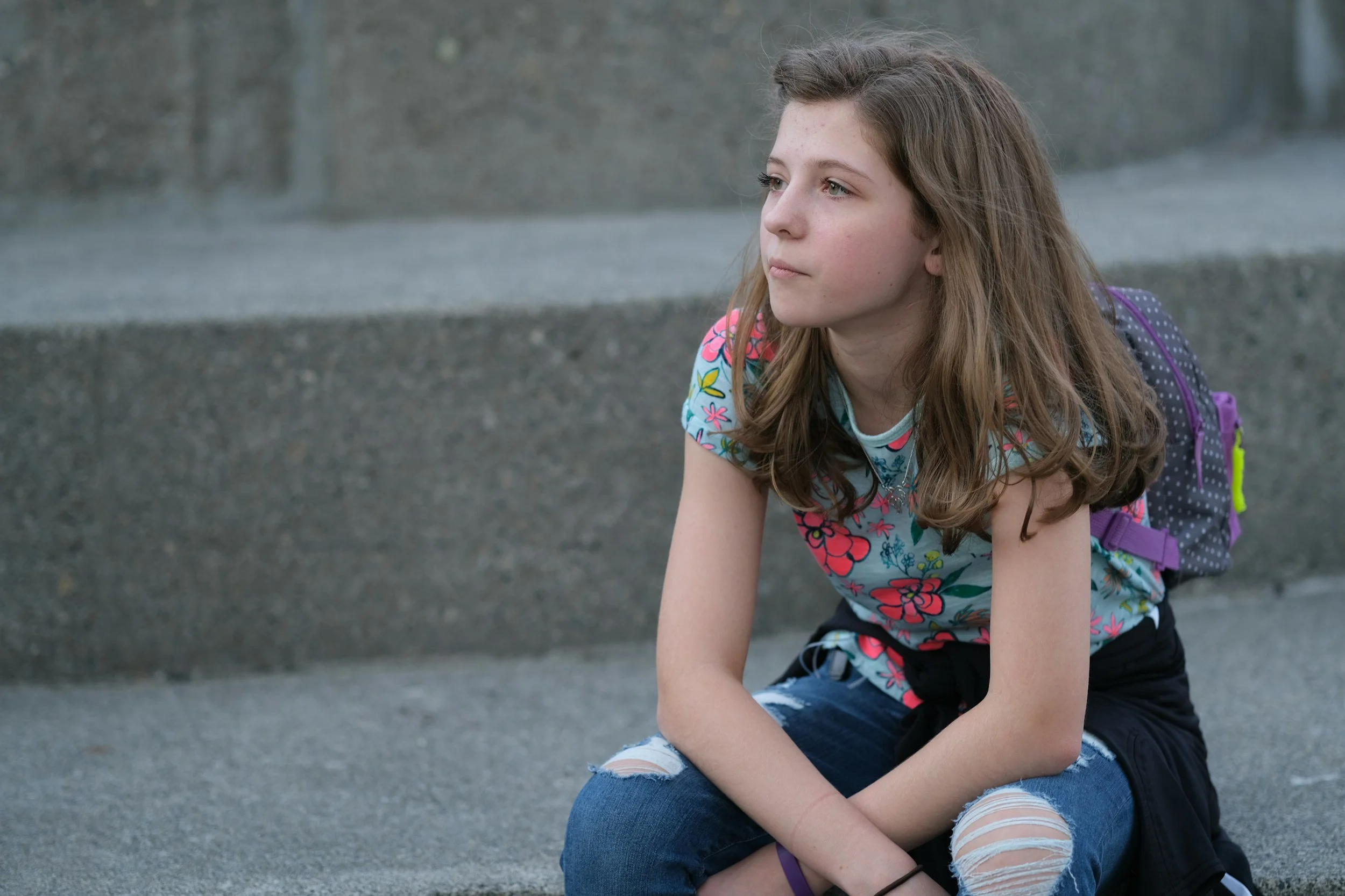 young teen girl sitting on steps looking thoughtful