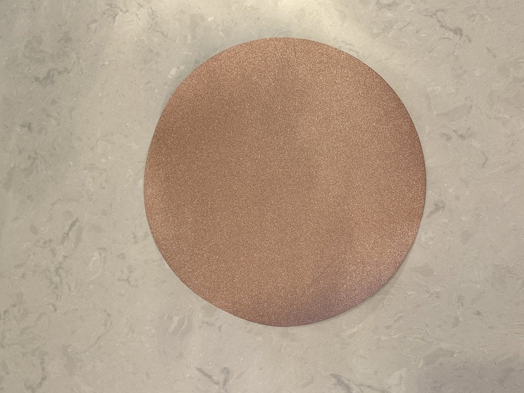 A round sandpaper disc on a light marble surface.