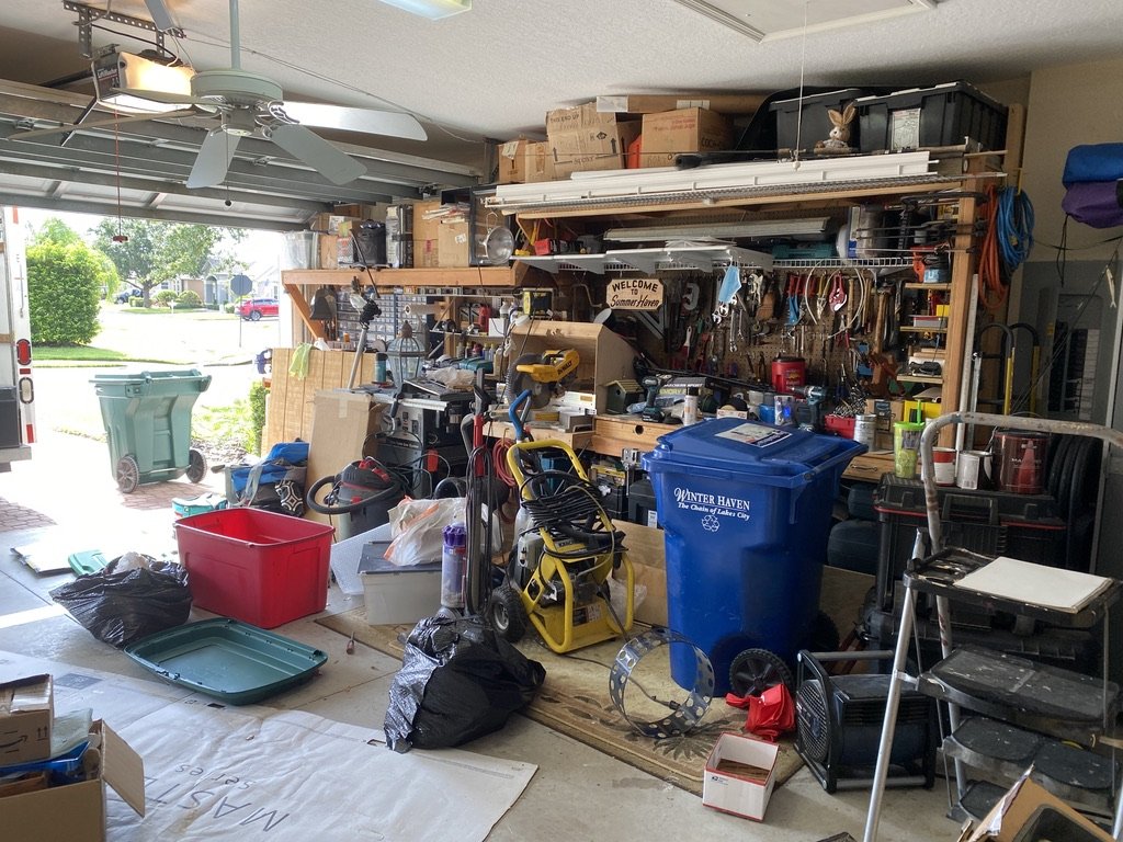 Cluttered garage with tools, boxes, and bins