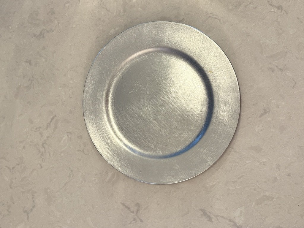 A plain, round metal plate on a light-colored marble surface.