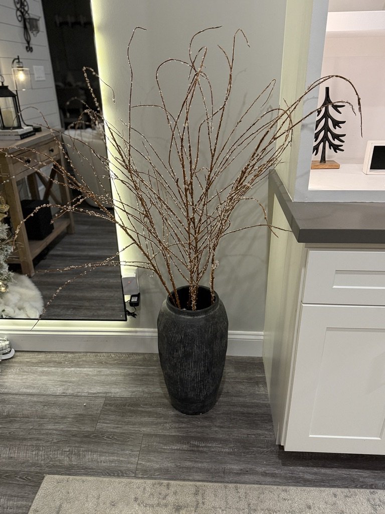 Tall dark vase with decorative branches in a modern interior space.