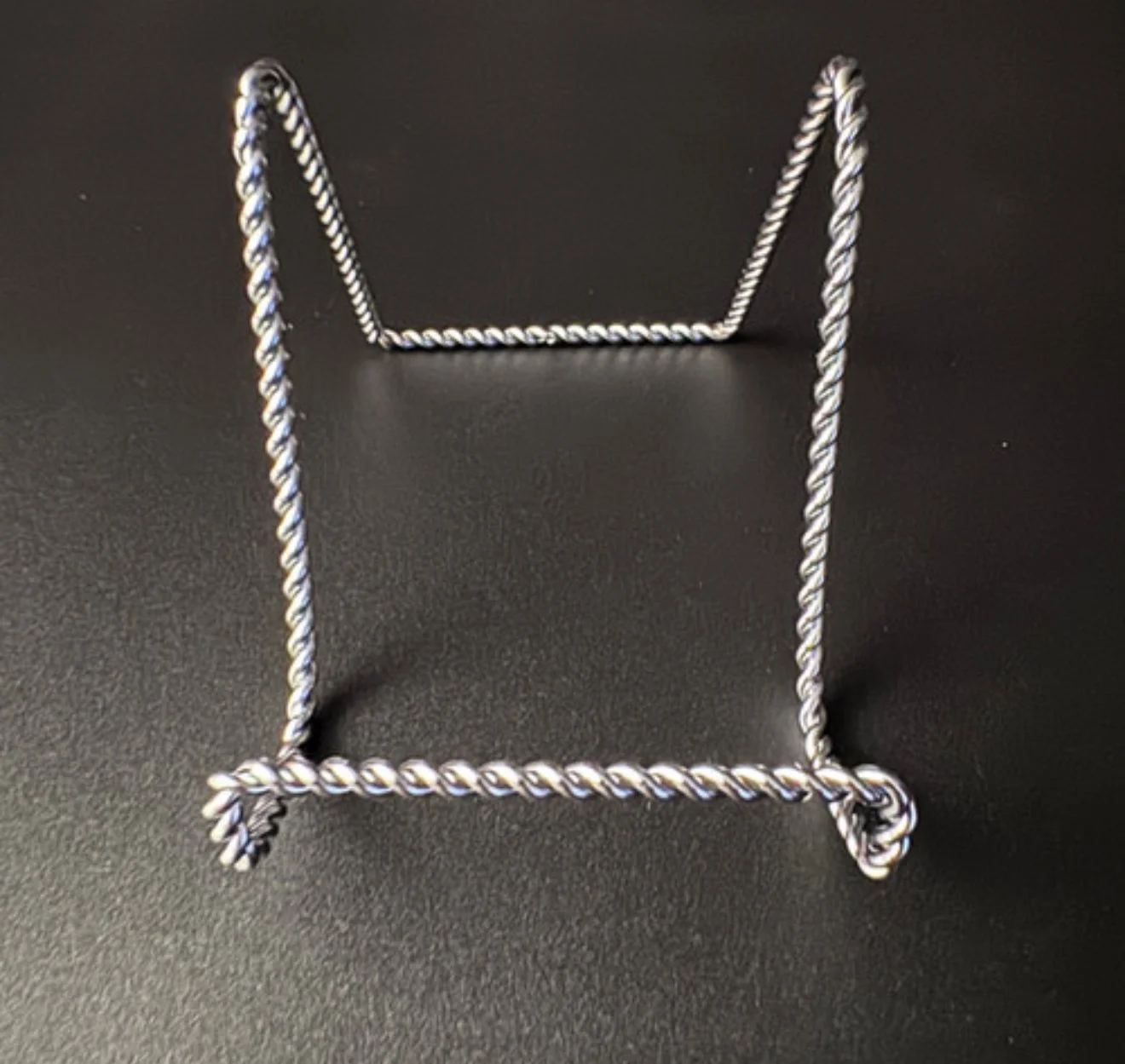 Twisted metal wire stand on a dark surface.