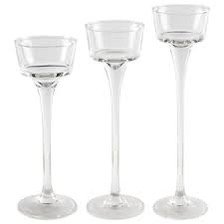 Three clear glass candle holders with varying heights positioned on a white background.